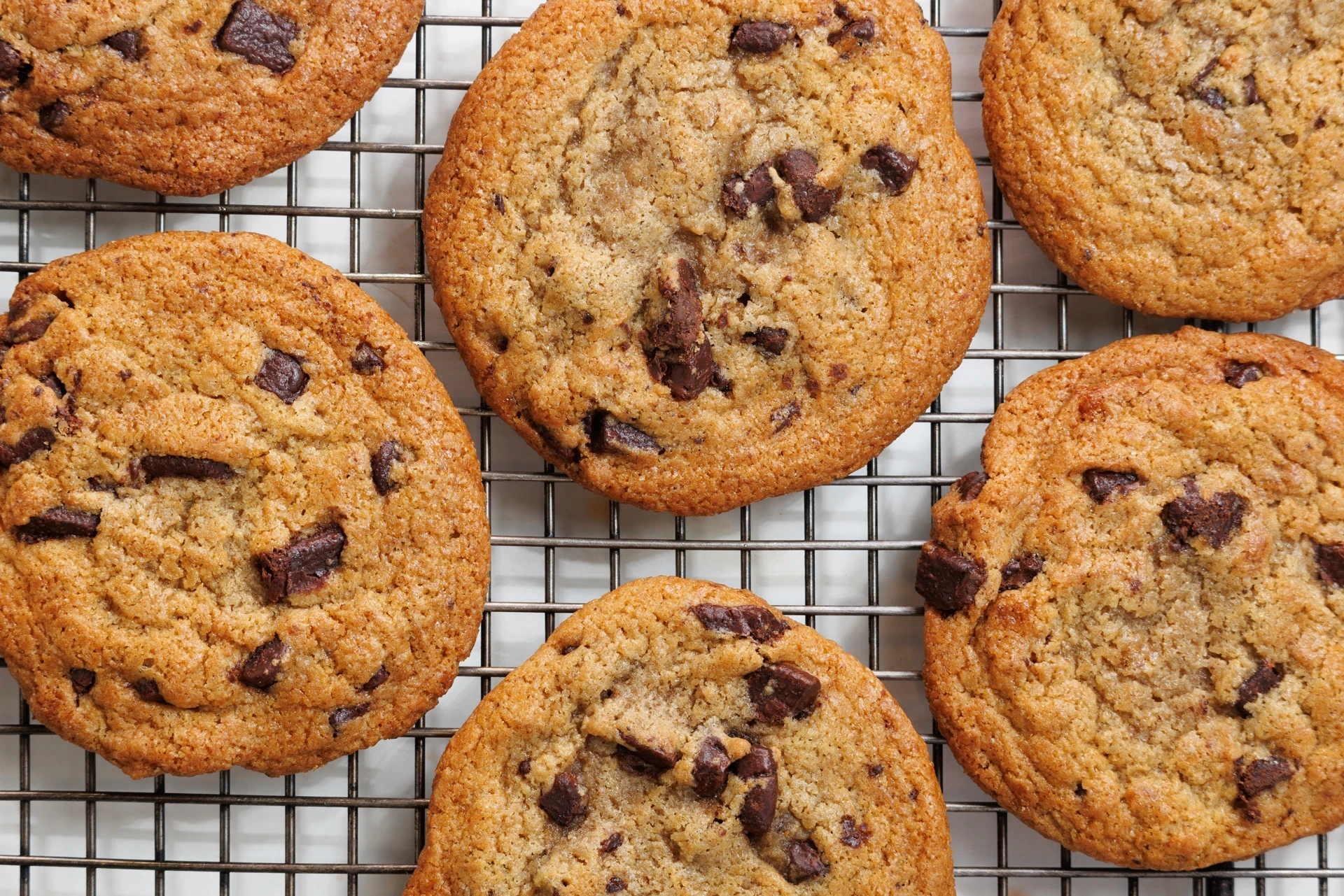 Close up view of chocolate chip cookies laid on top of a metal grill.
