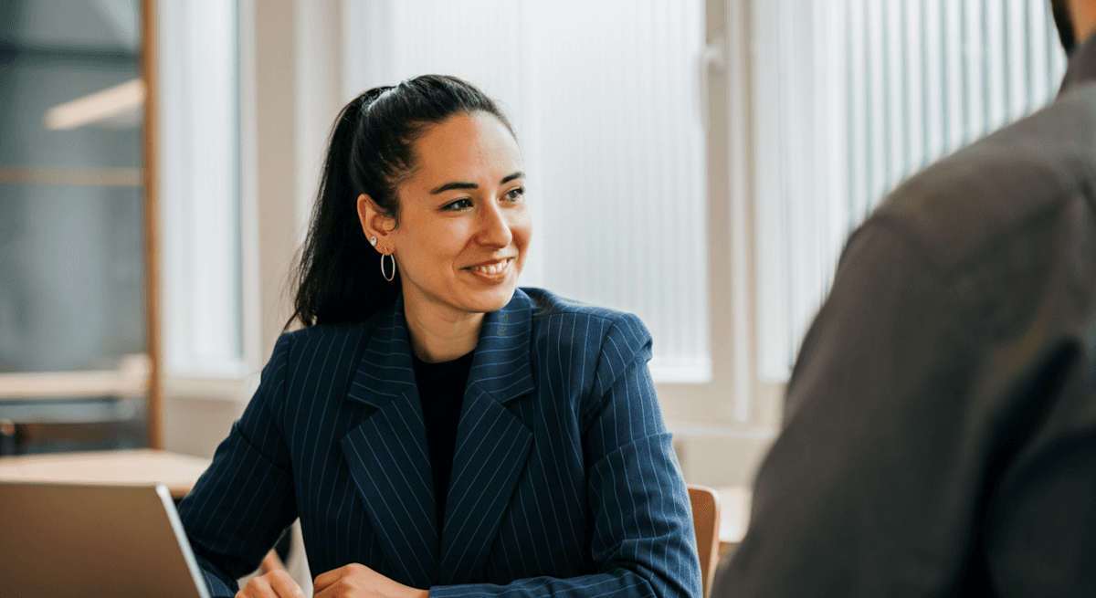 A close-up portrait of a smiling older woman with wavy grey hair.