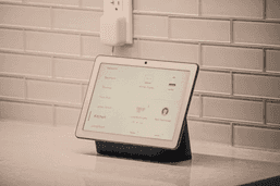 A modern smart home living room with AI-connected devices — speaker, lights, and camera