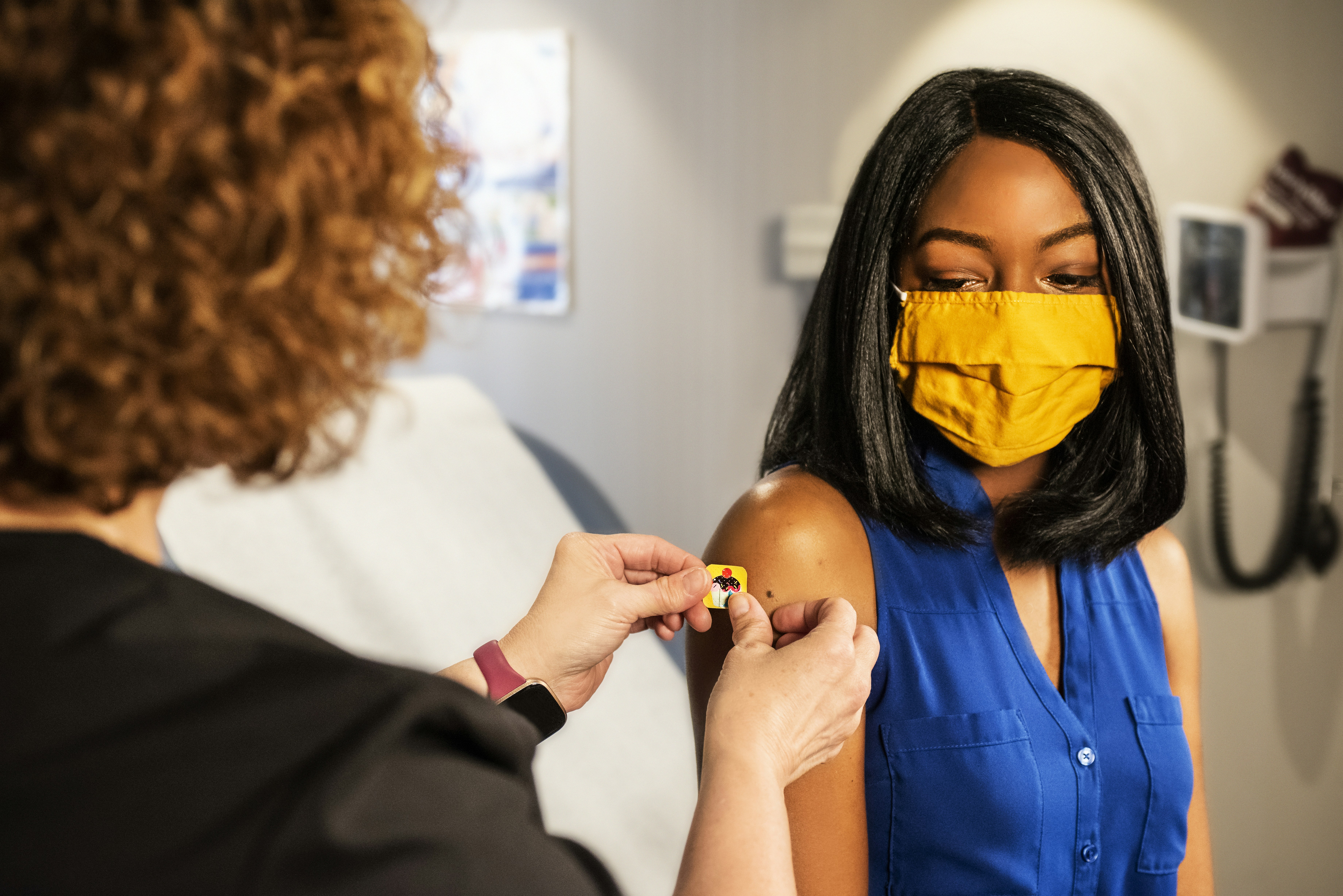 Black Girl getting a band aid after a vaccine shot