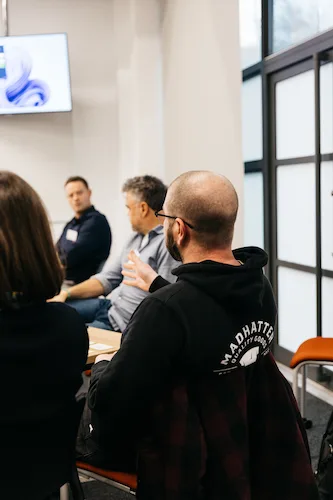 People sitting down in a classroom, one person looking at something.