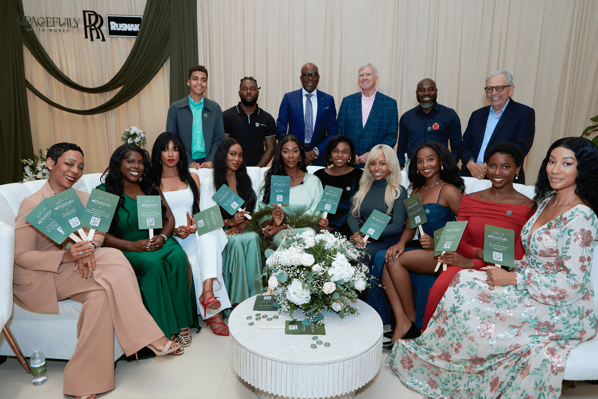 Grace Circle California attendees gather for group photo, holding event fans inside Rolls-Royce Pasadena showroom.