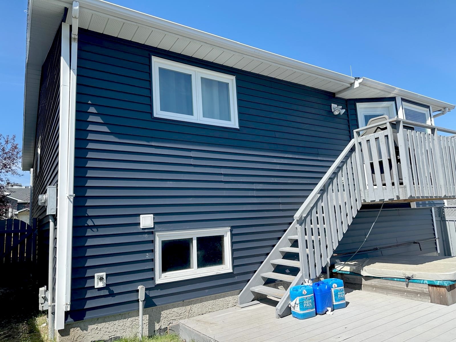 Vinyl re-siding on a Calgary split-level home in deep blue with fresh white trims.