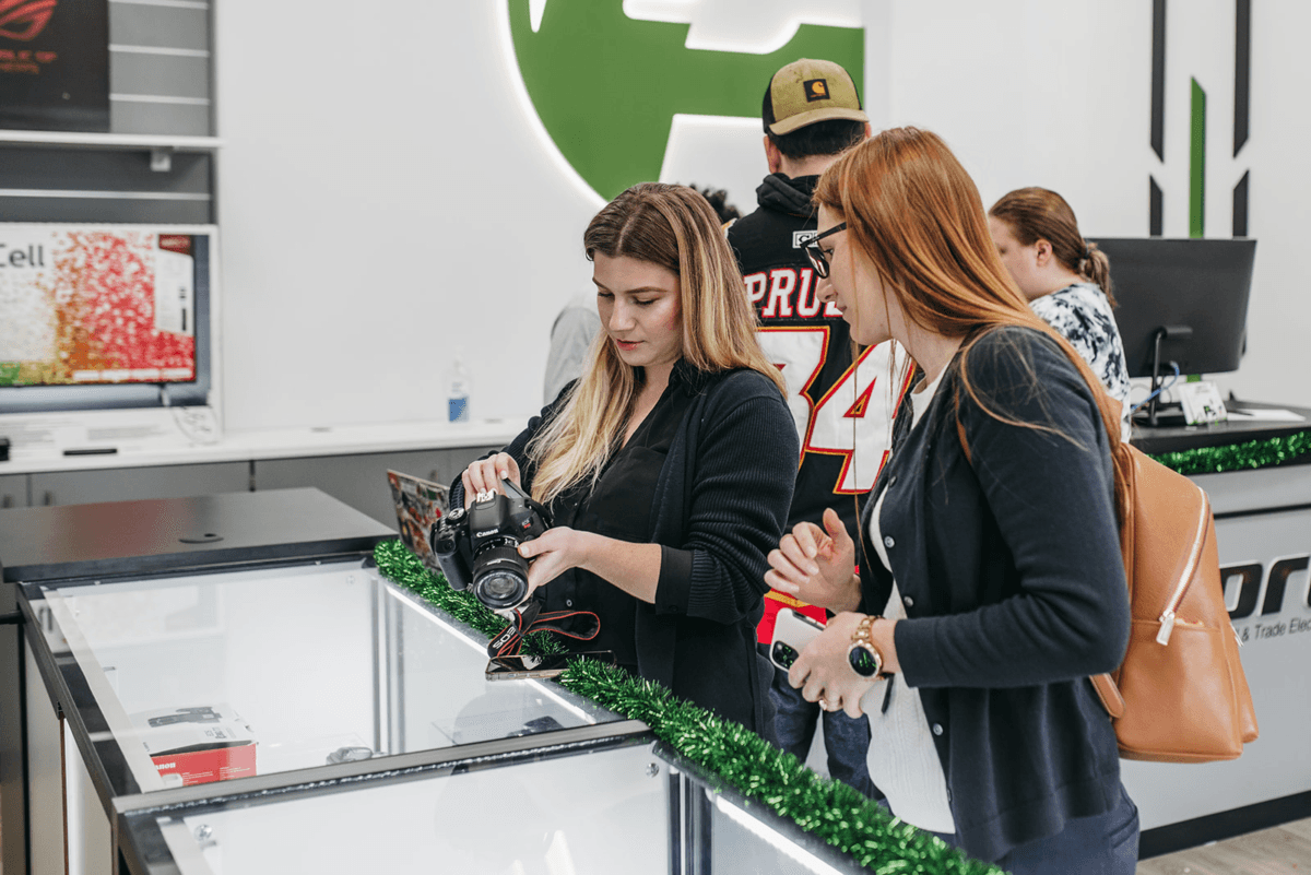 Customers examining a camera at a PayMore store