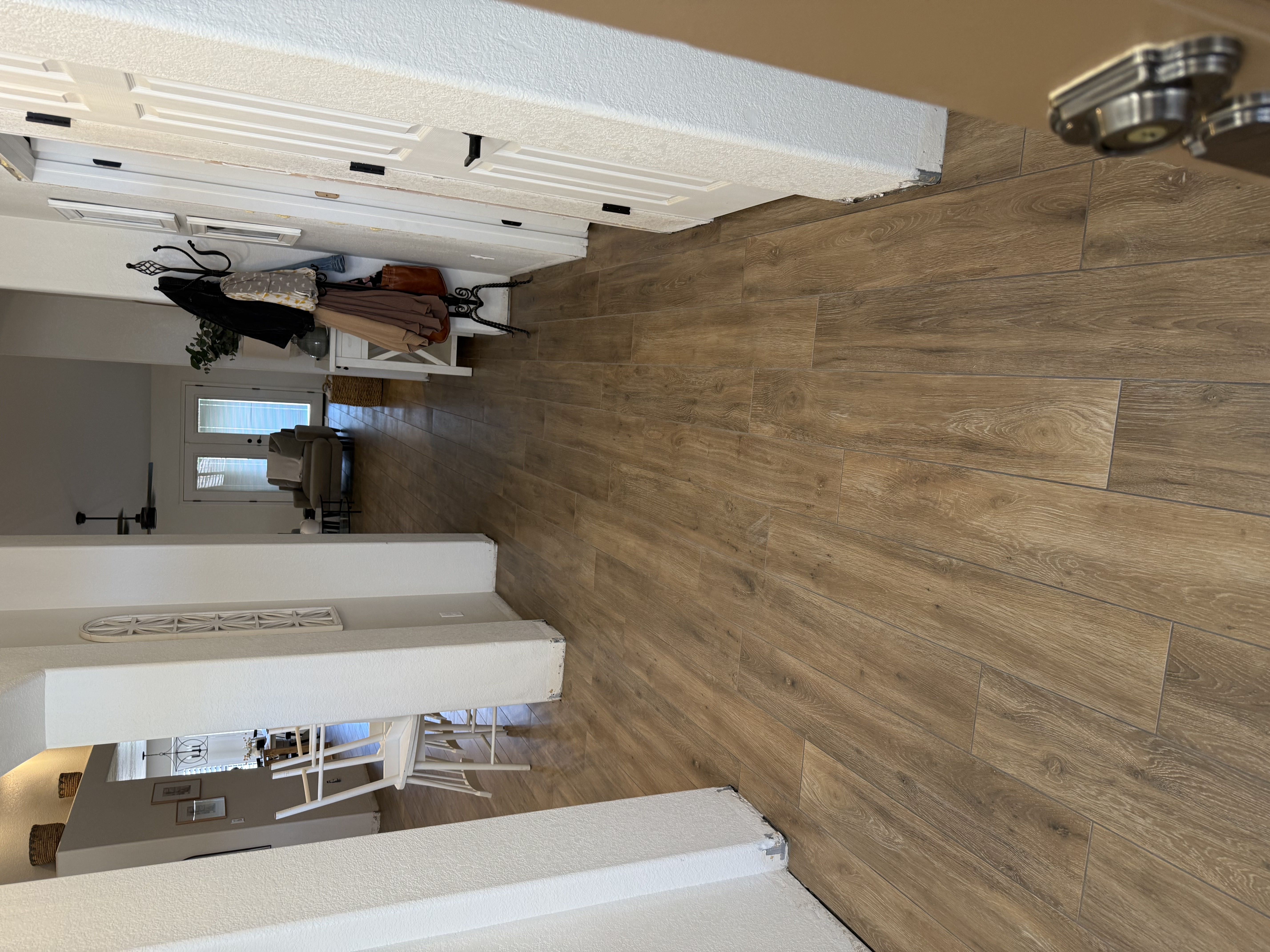 Modern living area with gray wood-look tile flooring, large sliding glass doors, and open space in a new home under construction.