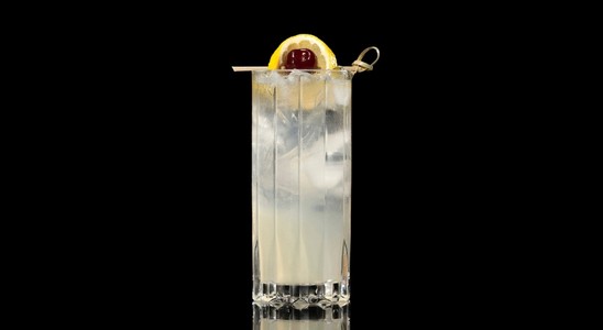 A closeup of a Vodka Collins drink against a dark background.