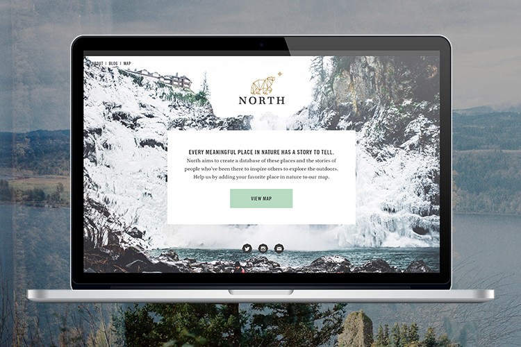 A laptop screen displays a webpage titled “NORTH” with a logo featuring a bear silhouette. The page includes a navigation bar with “VIEW MAP” and a text description: “EVERY MEANINGFUL PLACE IN NATURE HAS A STORY TO TELL.” Below the text, a paragraph explains the platform’s mission: “North aims to create a database of these places and the stories of people who’ve been there to inspire others to explore the outdoors. We’ve built our favorite place in nature to our map.” A water image and mountains are visible in the background.