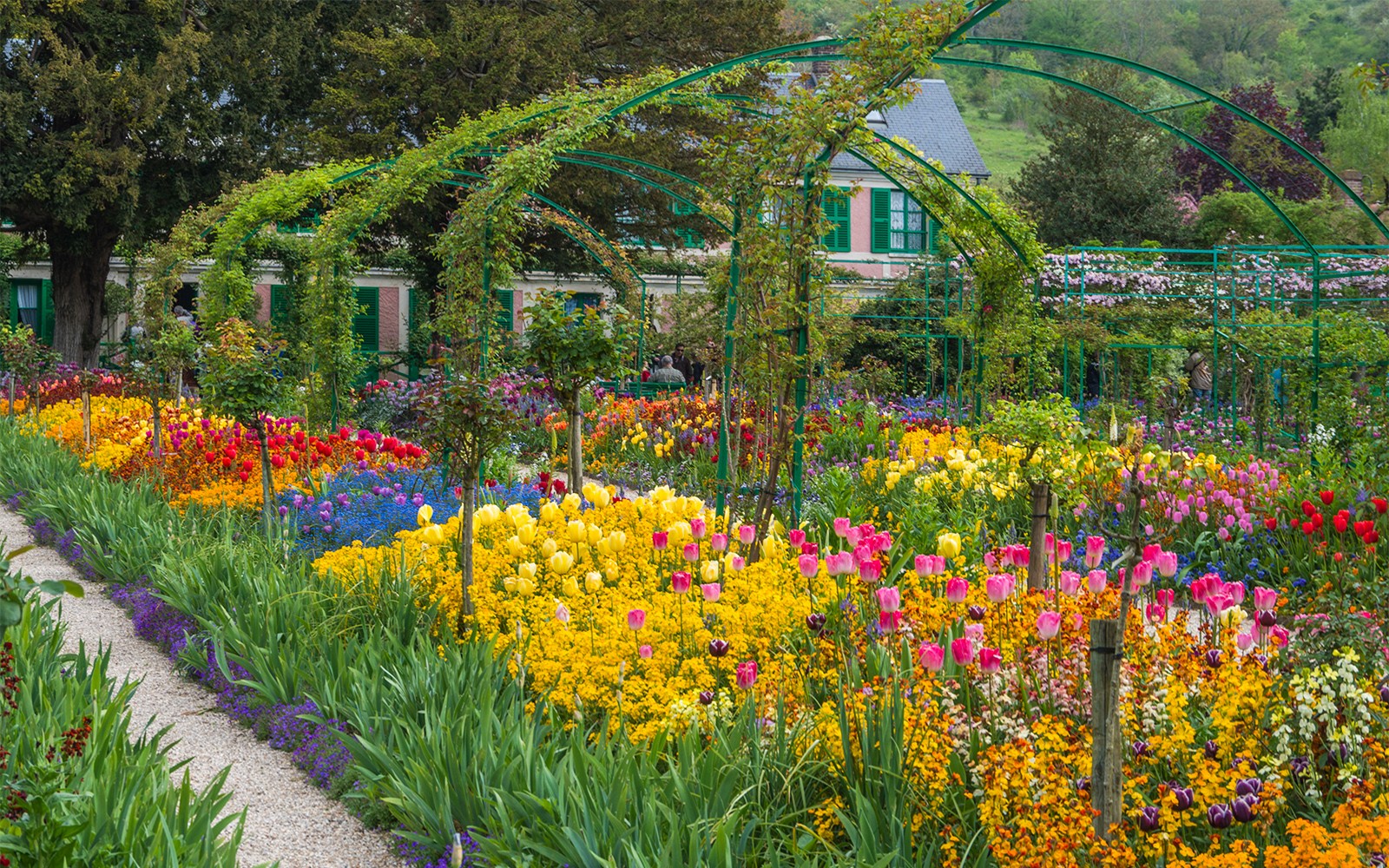 Giverny gardens with vibrant flowers and Monet's house in the background, part of a Paris half-day tour.