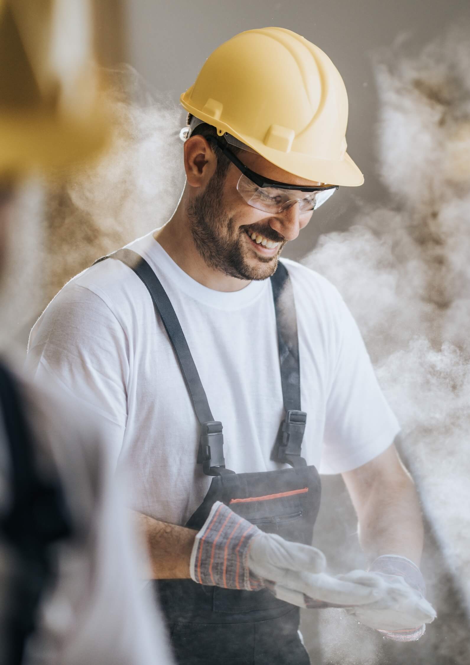 Lächelnder Handwerker nach Bauarbeiten mit Staubschutz – Symbolbild für professionelle Baureinigung und Übergabefertigkeit