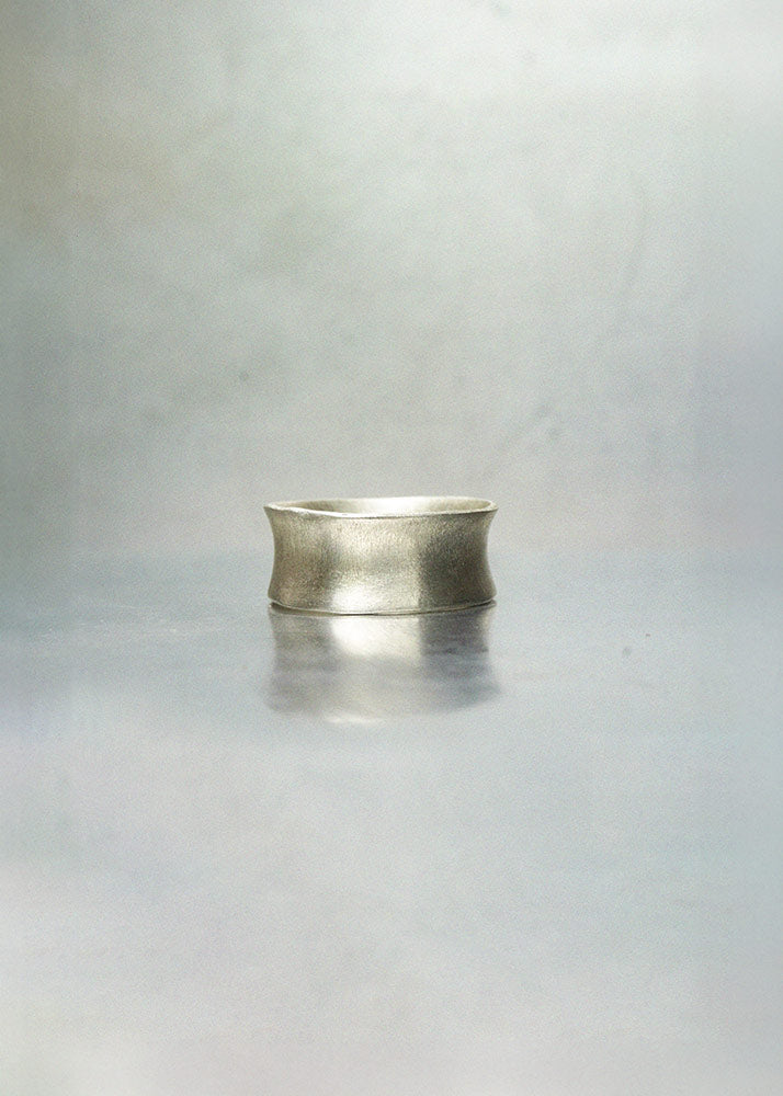 Silver ring on a reflective gray surface with a blurred background