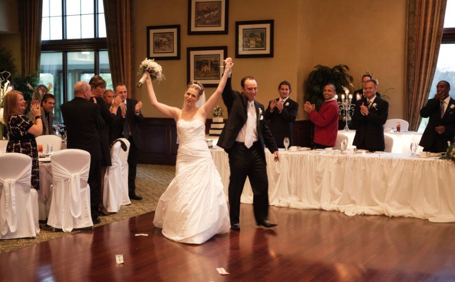 Bride and groom walking into their reception to cheers