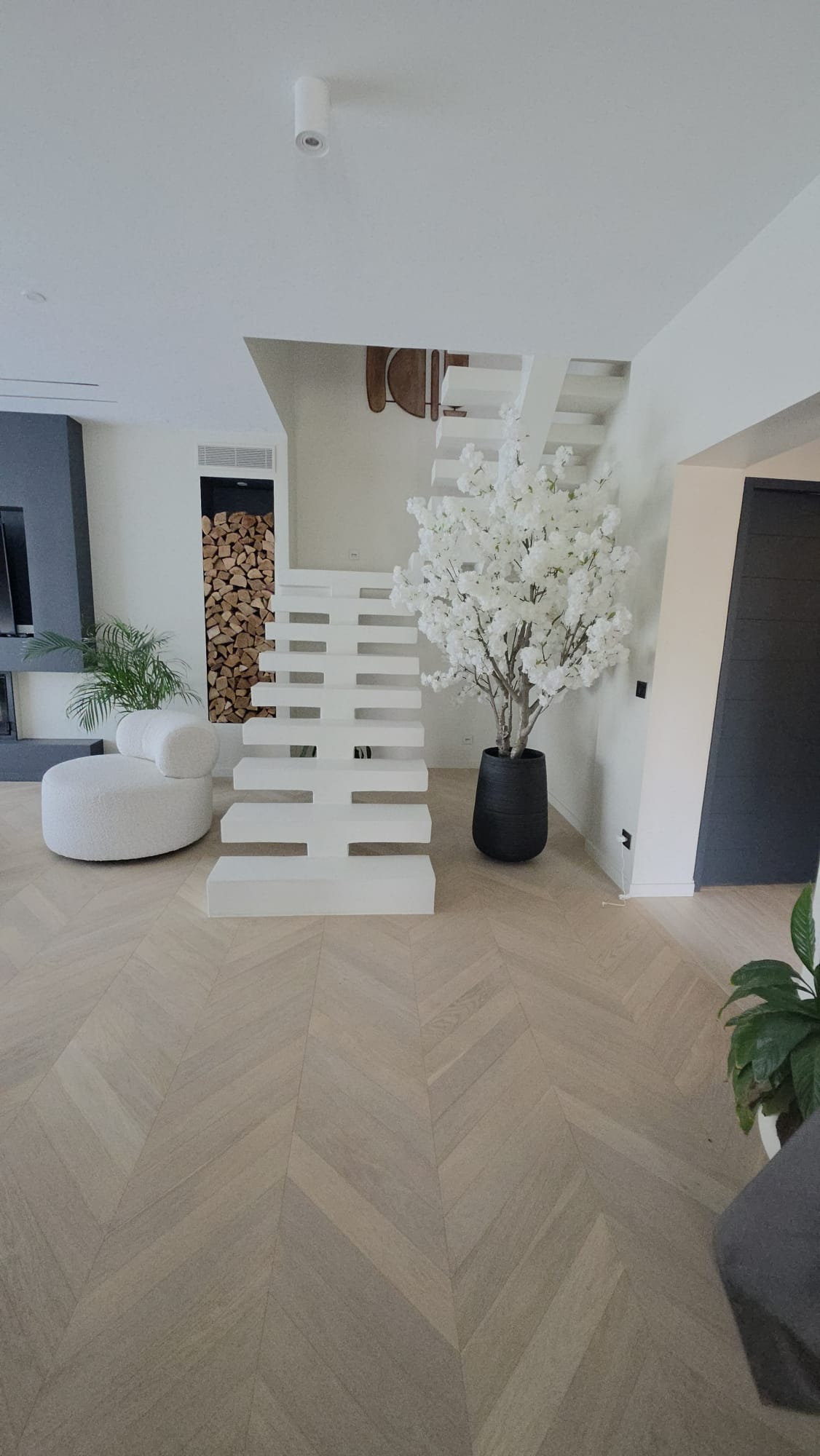 Parquet contrecollé posé en chevron au pied d'un escalier blanc à Montmagny (95)