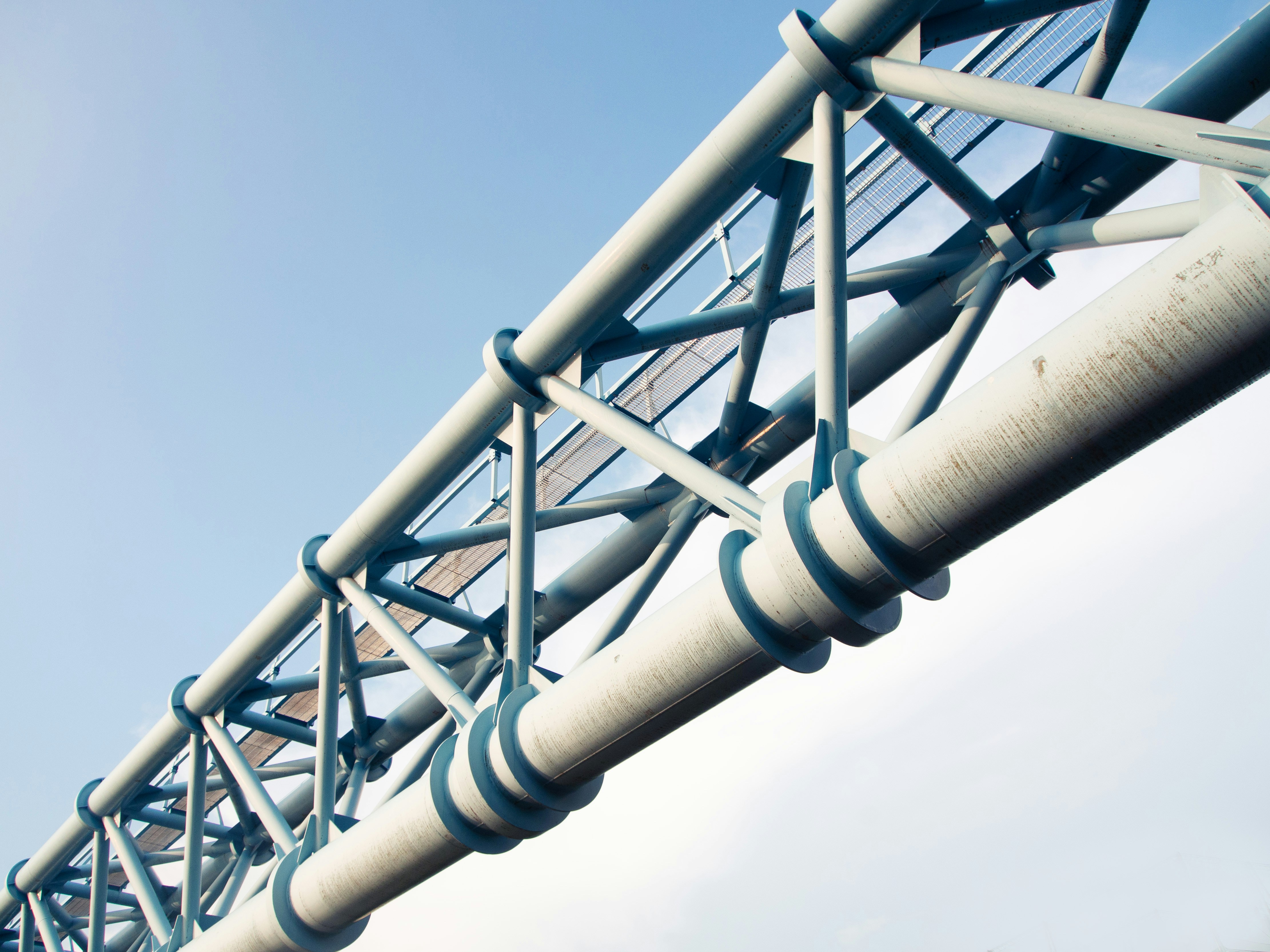 Close-up portrait of a person wearing a gray insulated hooded jacket with the hood up, showing their face framed by the hood against a light background.