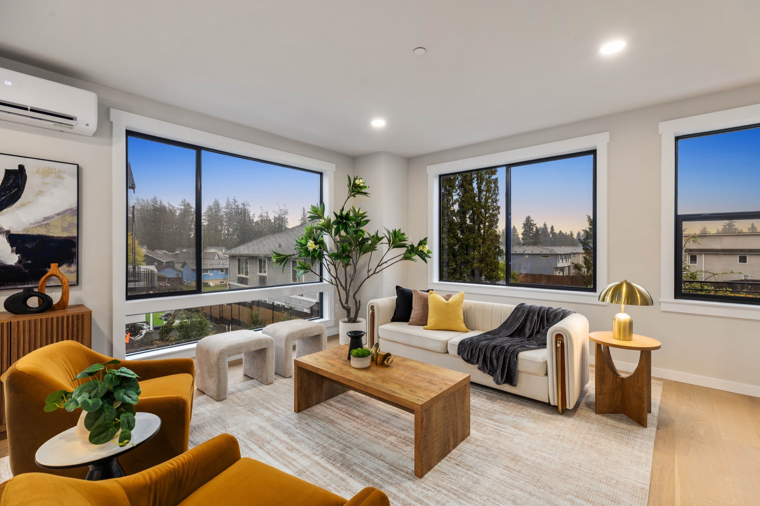 Contemporary luxury living room at dusk featuring a marble-surround electric fireplace, neutral sectional sofa, amber armchair, and large picture windows with city views