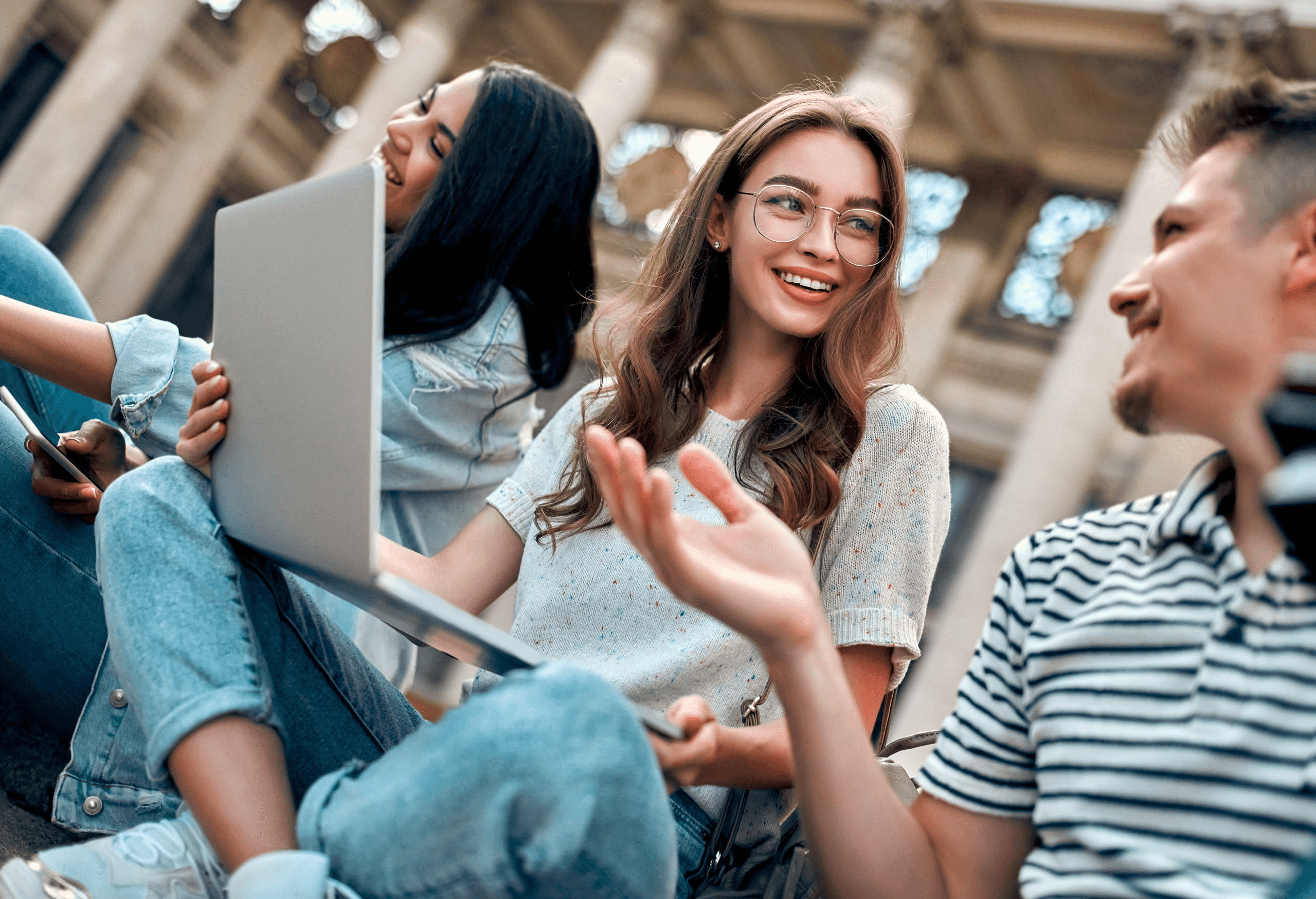 Three college students working together outdoors with a laptop