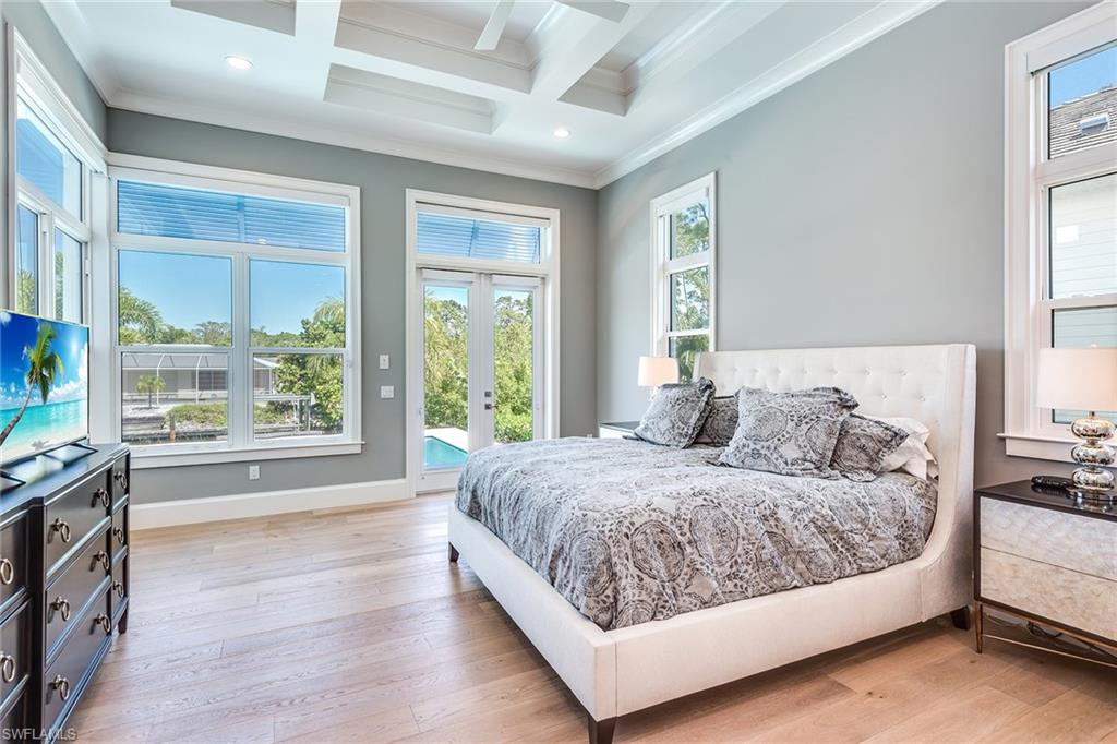 a bedroom with multiple windows and wooden floors