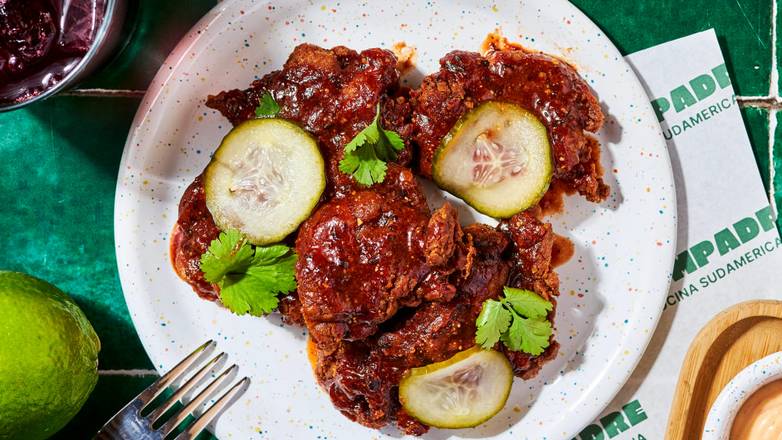 Compadre Fried Chicken, spécialité emblématique du restaurant latino Compadre à Paris : cuisse de poulet mariné et frit, servie avec une sauce pimentée au miso et aji panka, accompagnée de pickles et coriandre fraîche. Idéal pour partager dans une ambiance street food sud-américaine