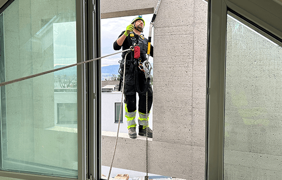 Four diverse professionals collaboratively working on a laptop, with one person pointing at the screen while others observe.