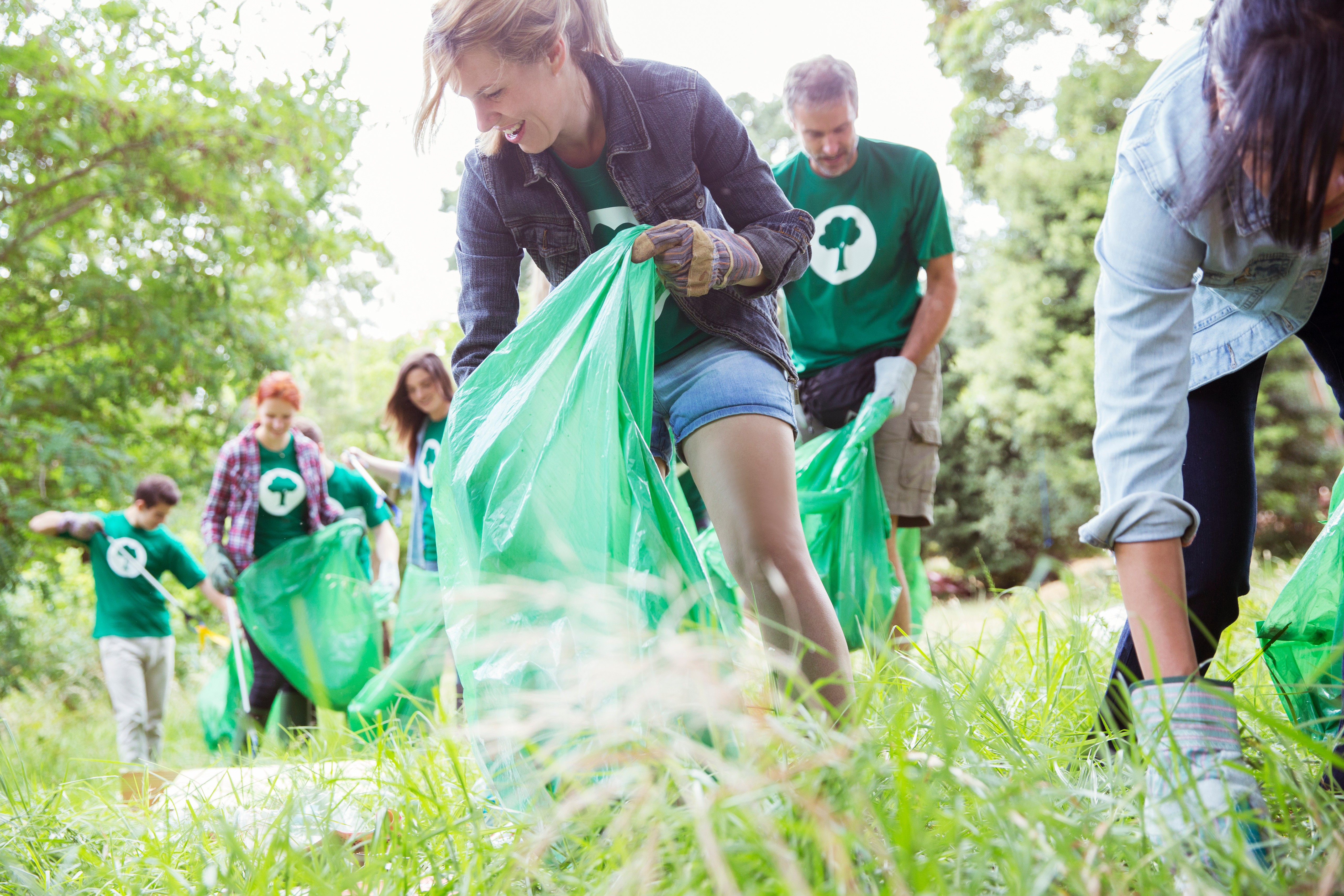 Environmentalist volunteers picking up trash in field.