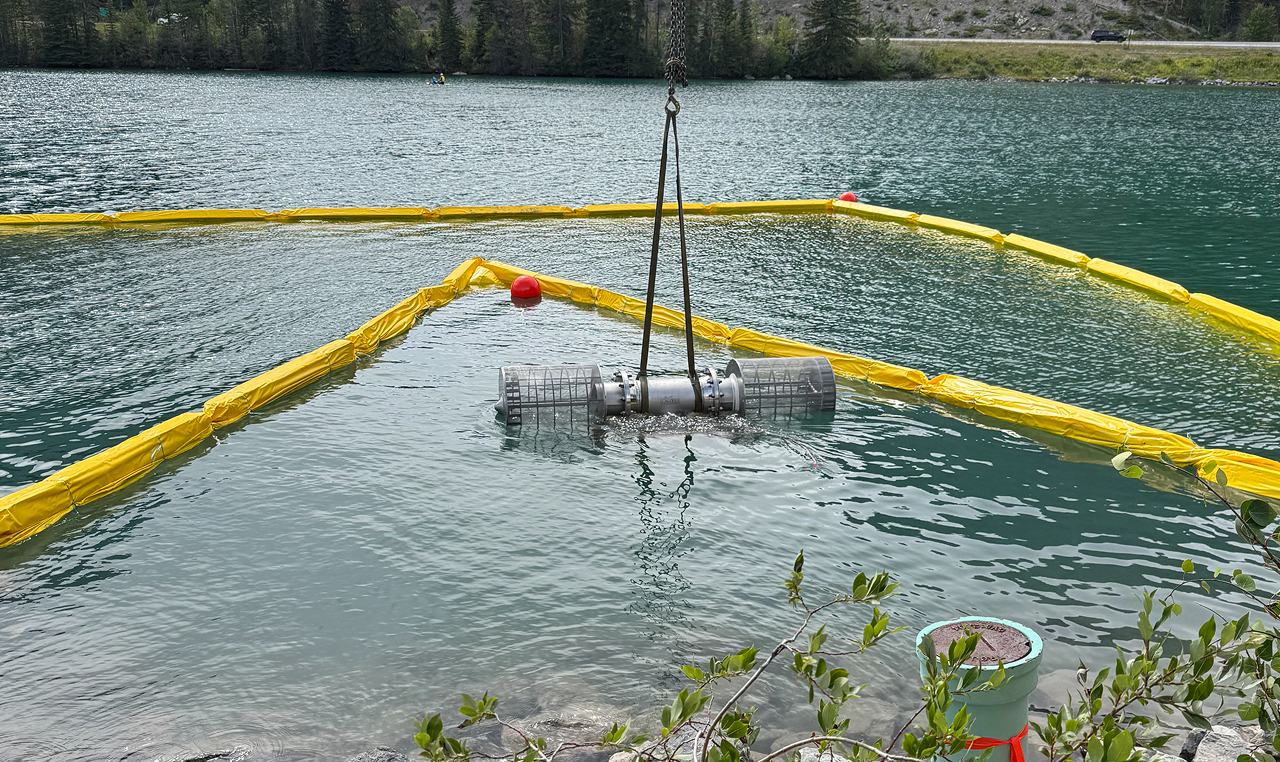 Fish screen installation being lowered into water within turbidity curtain at Canmore Nordic Centre intake