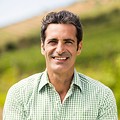 Smiling man in a green button-down shirt outdoors.