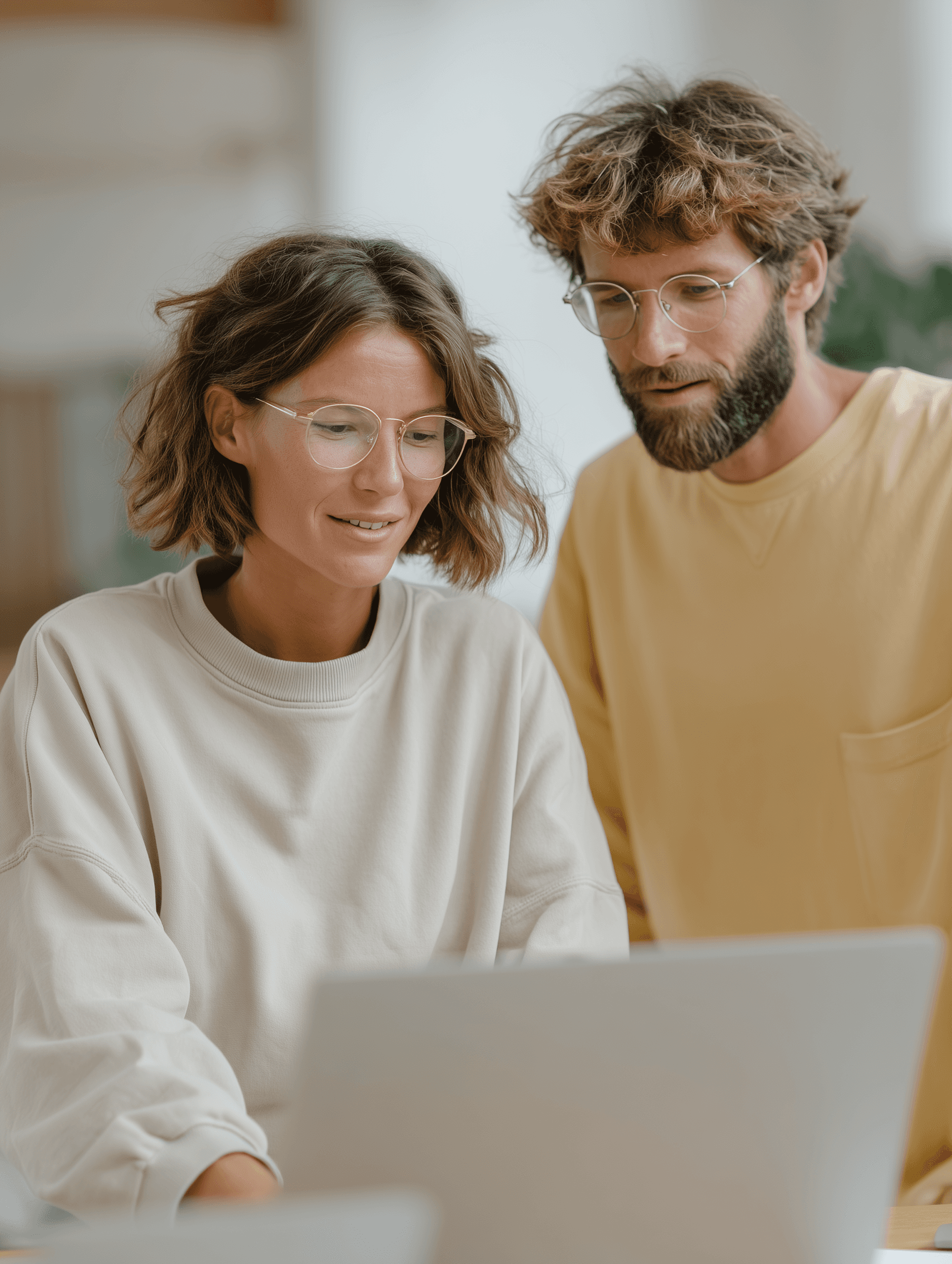 Man and woman with glasses looking at a screen.
