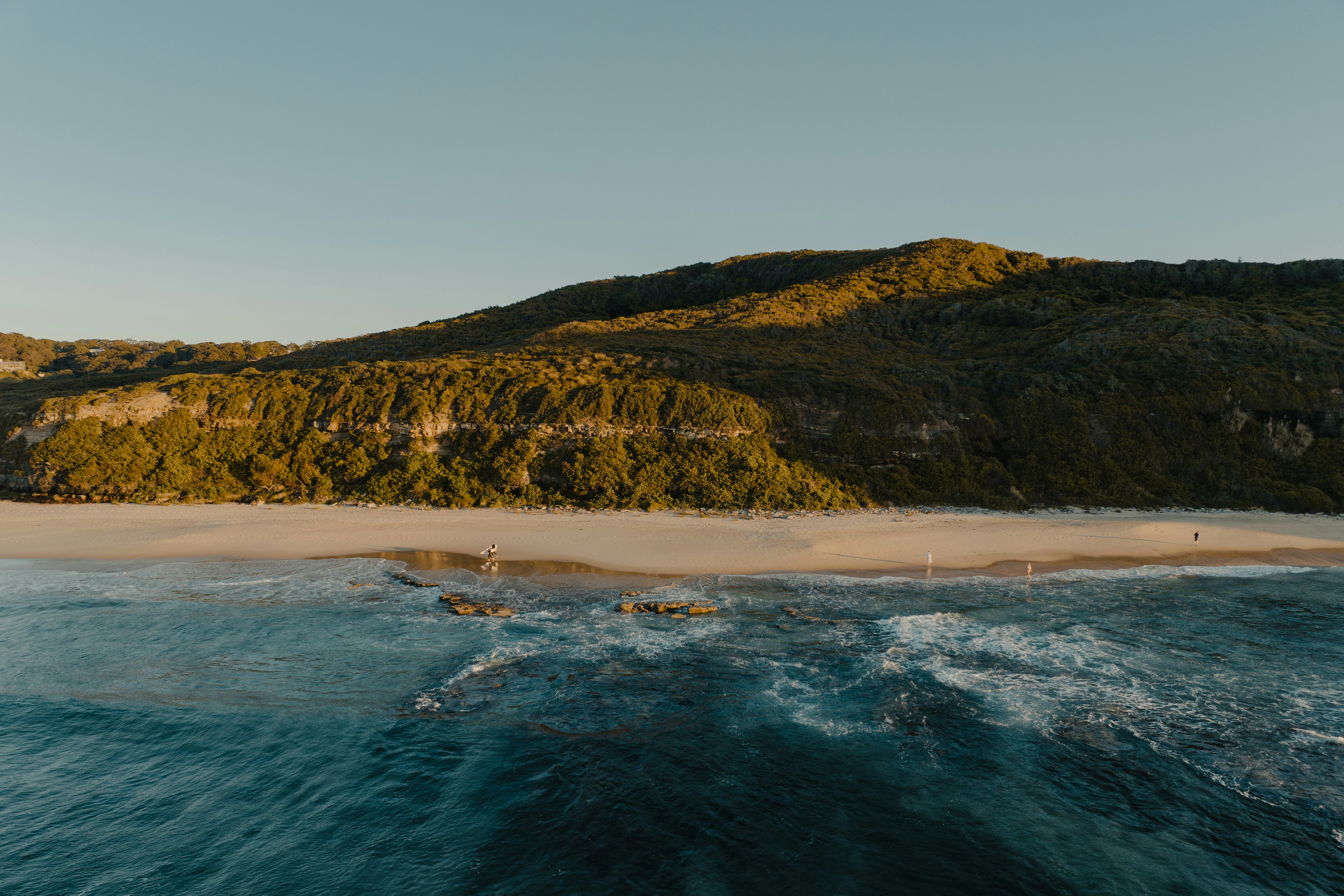 an aerial view of a beach with a mountain in the background