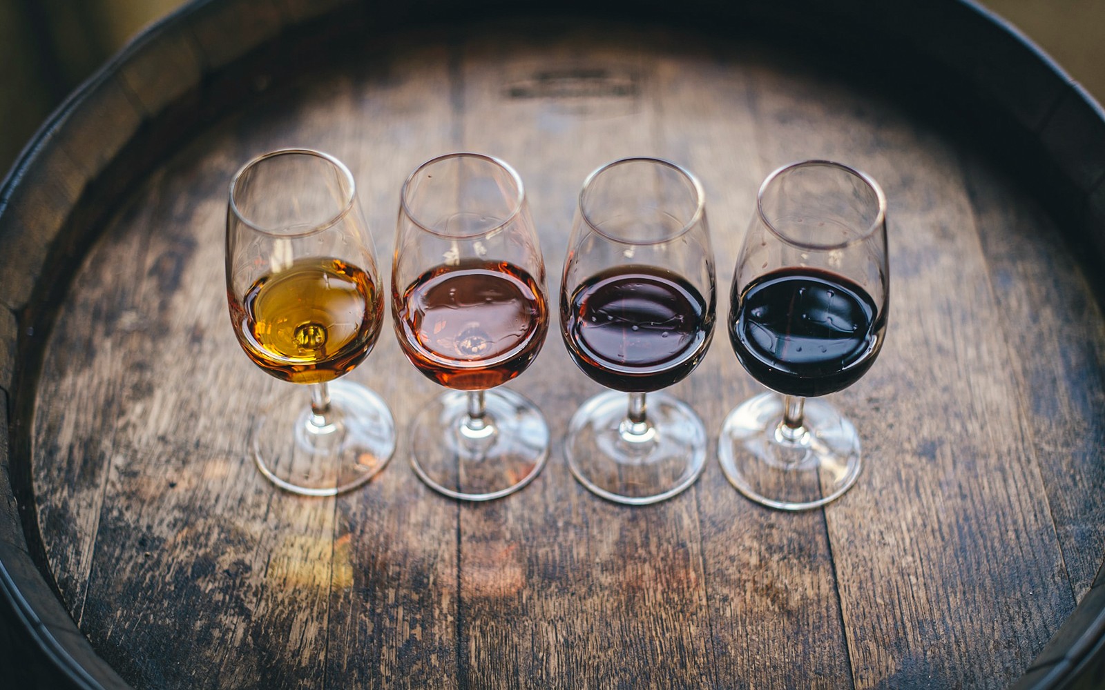 在奇扬蒂电动自行车之旅的葡萄酒品尝活动中,四个酒杯放在木桶上。