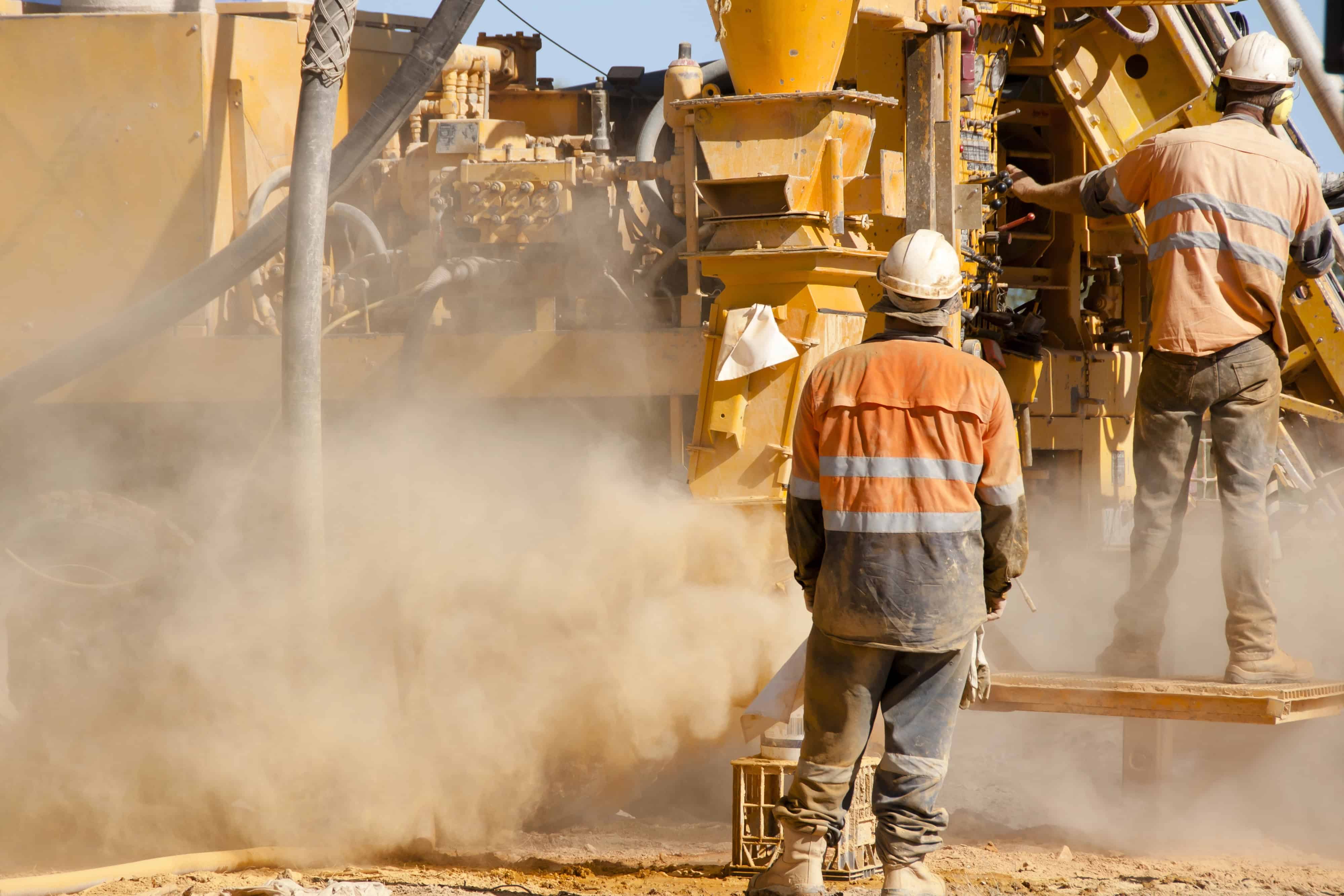 Reverse circulation drilling operations on an Australian mine site with driller and driller's offsider wearing high-vis and correct PPE