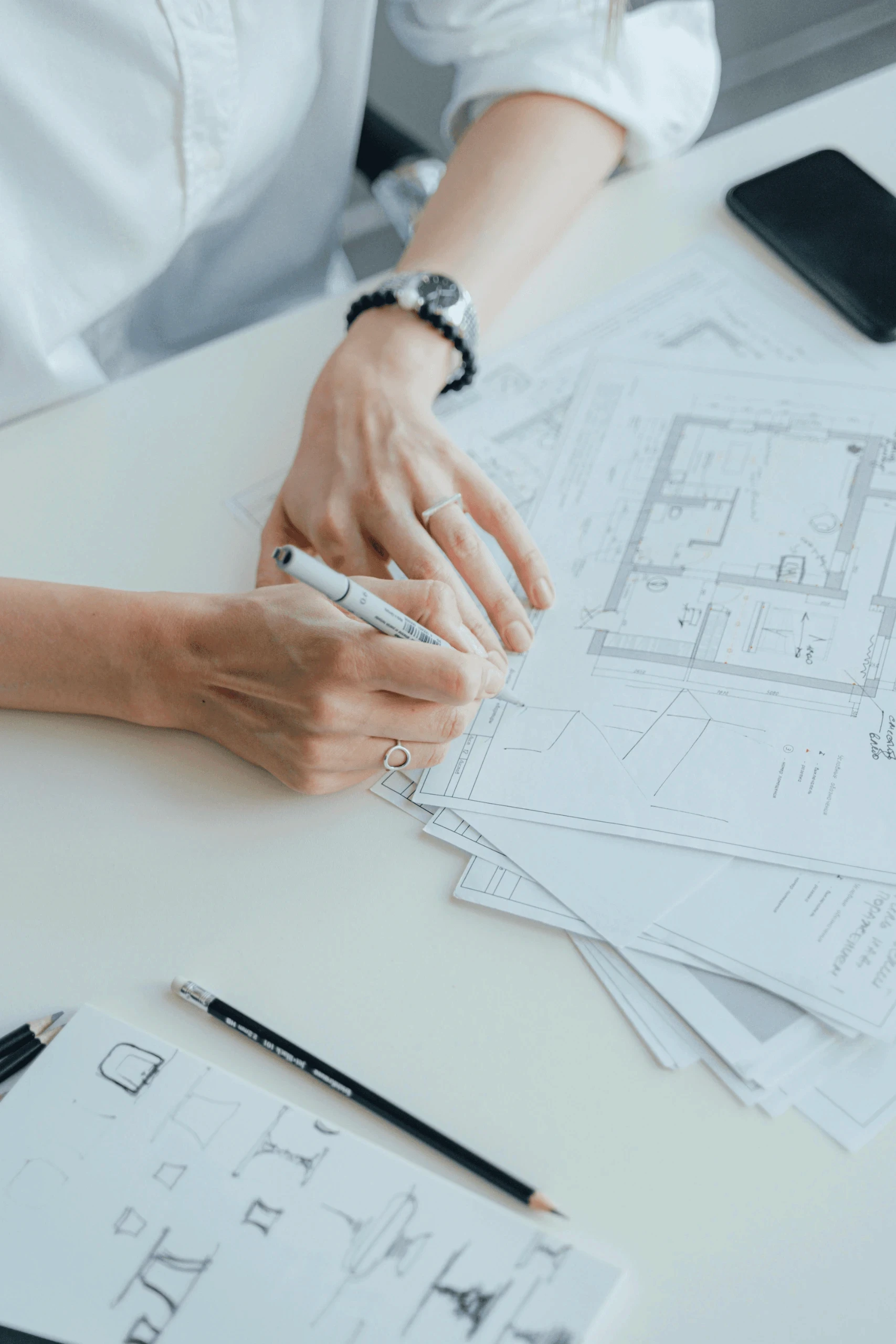 Hands reviewing architectural blueprints at a desk.