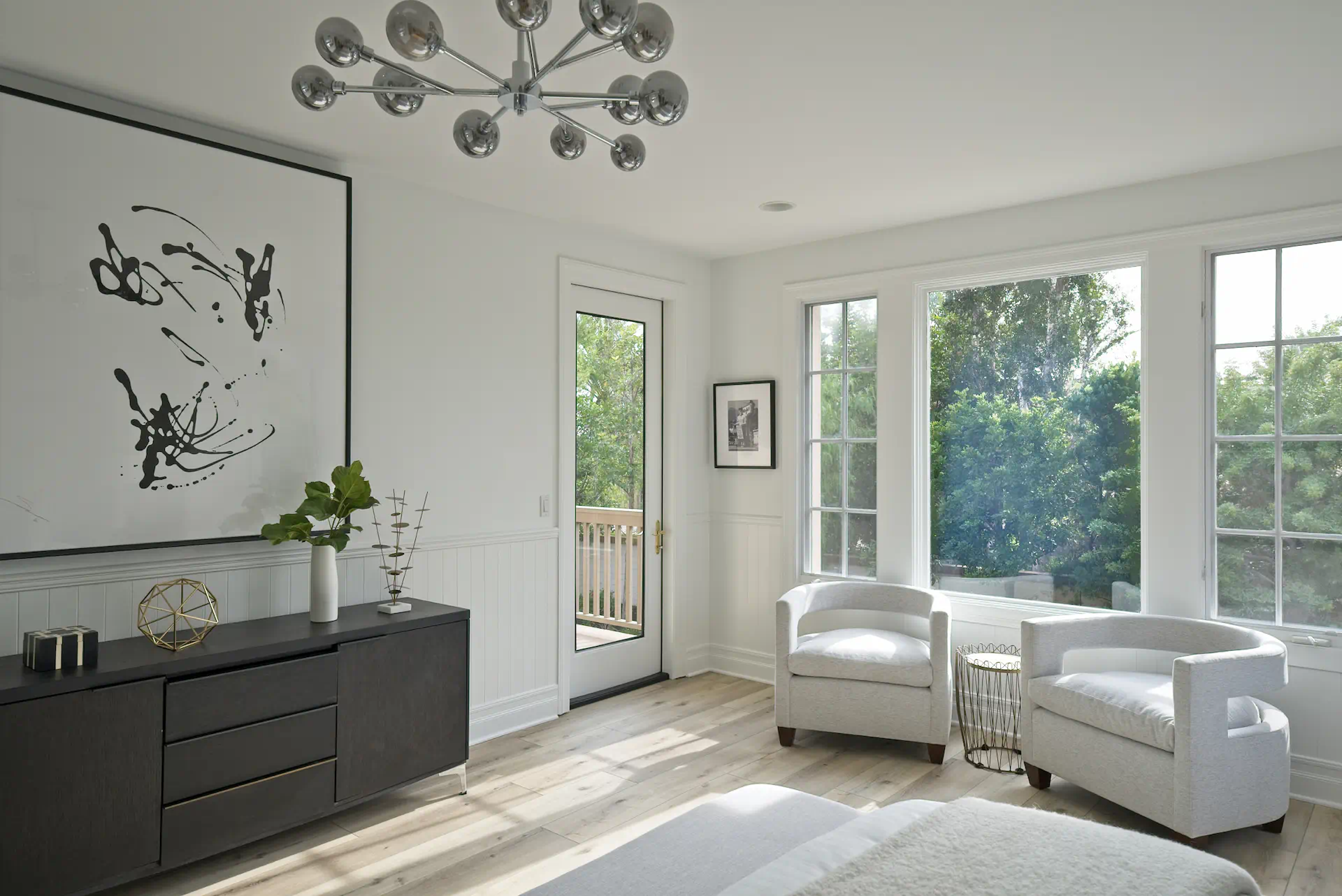View from angle 1 of the guest bedroom, showcasing a dresser and seating area near the windows that overlook the backyard, creating a serene and inviting space. Photo by Todd Huge.
