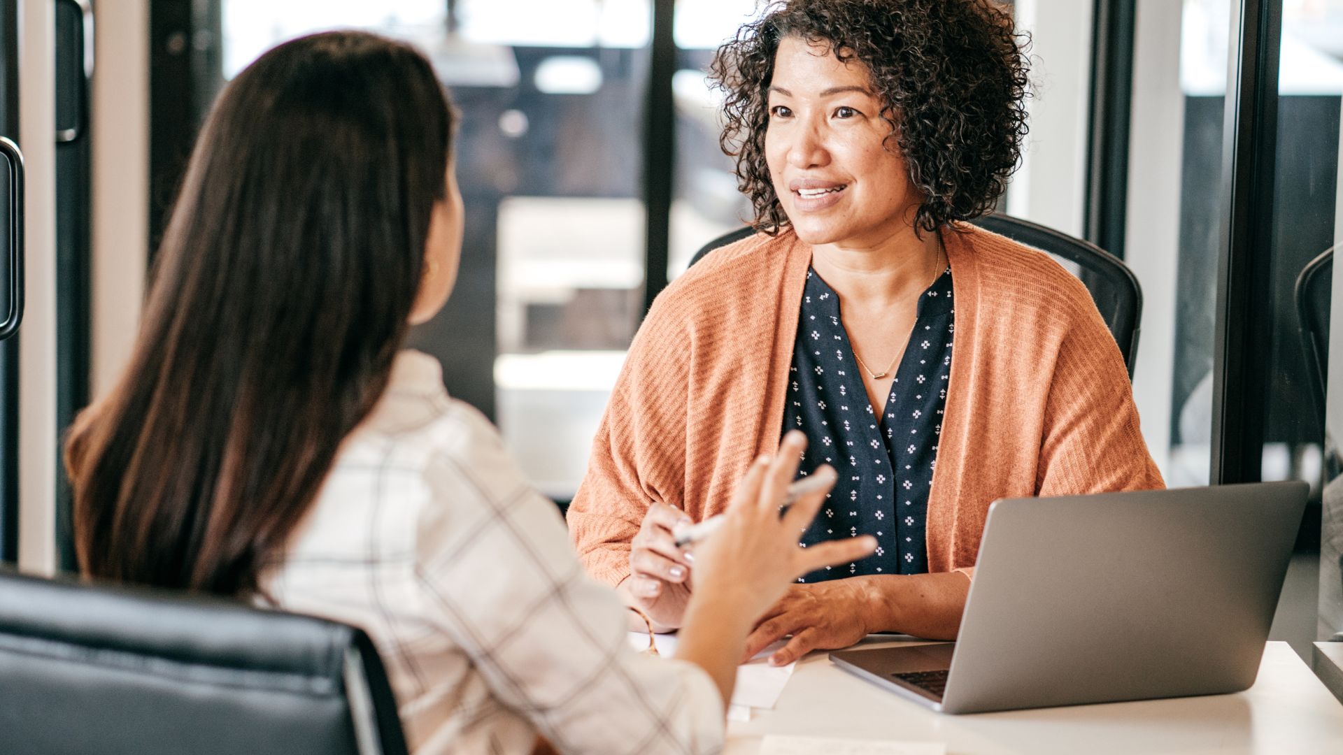 Two colleagues talking across a desk during a working conversation