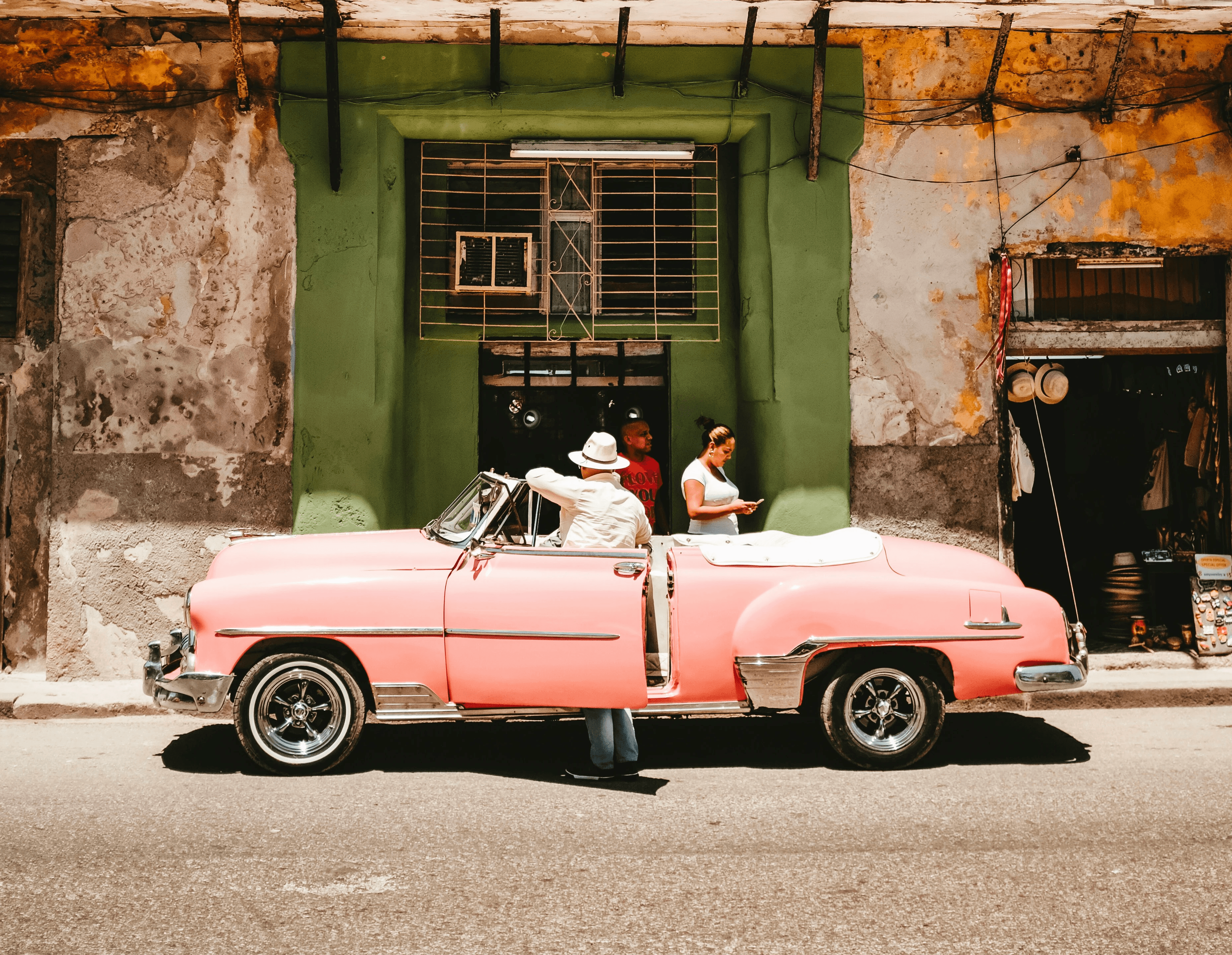 person standing beside of pink convertible car