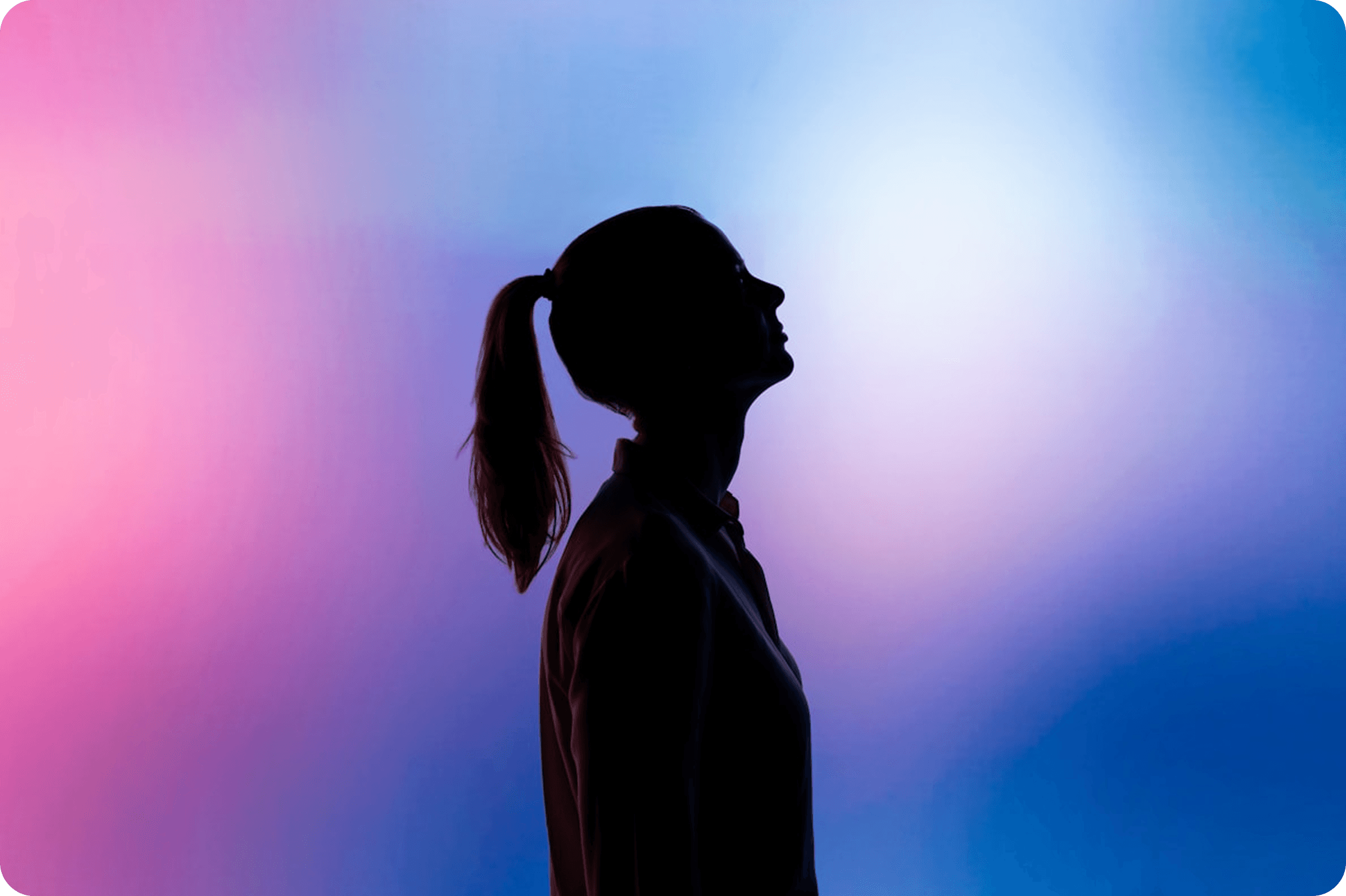 Silhouette of a person with a ponytail facing upward against a vibrant gradient background of pink, purple, and blue hues.