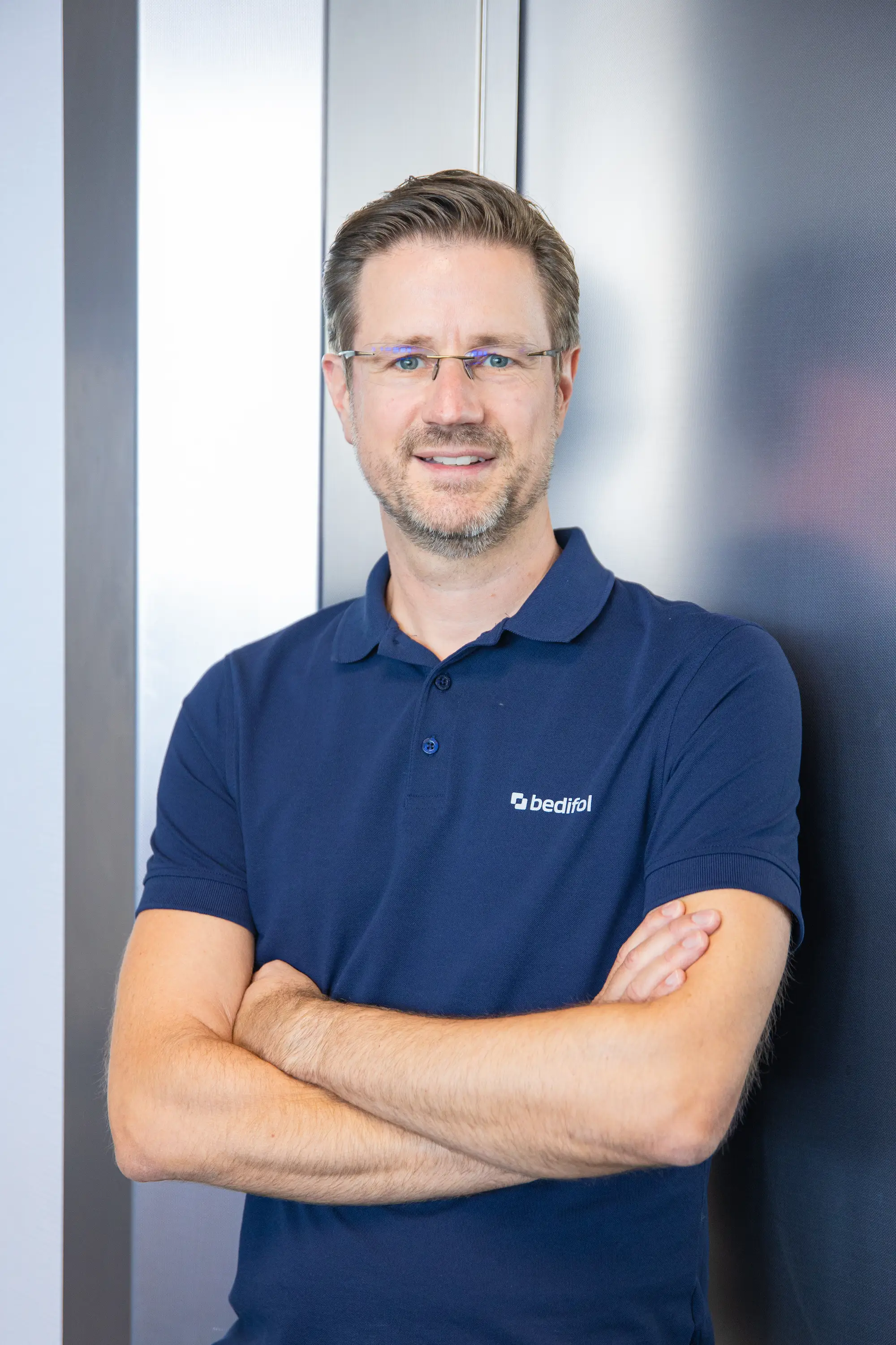 Thomas Berkenkämper wearing a dark blue Bedifol polo shirt, with his arms folded.