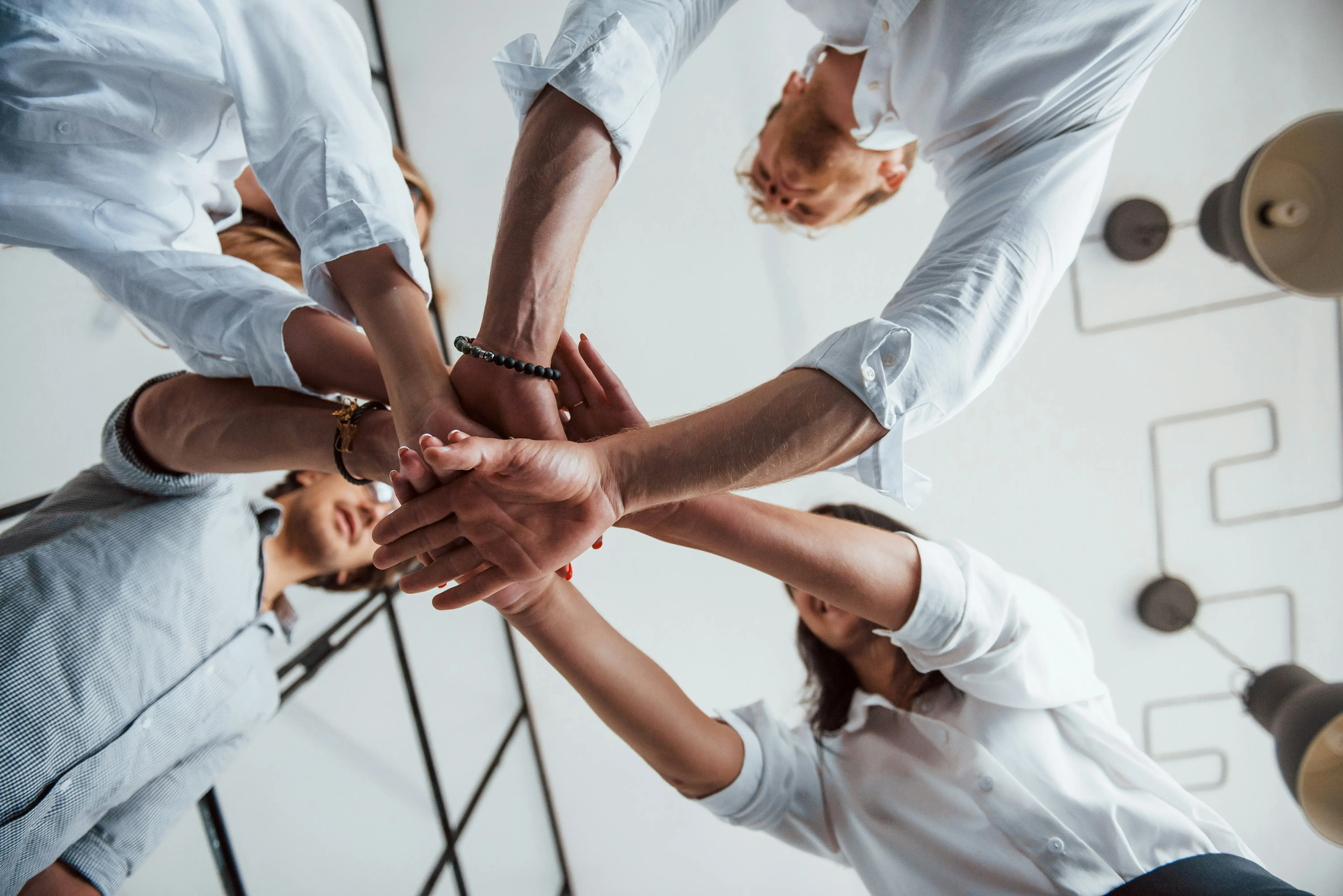 A group of professionals placing their hands together in the center of a circle