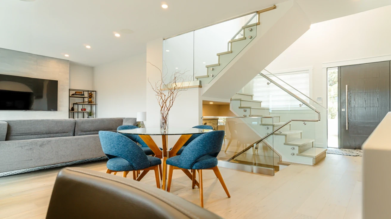Open dining area with glass table and modern staircase featuring glass railings in Vancouver Custom Homes Burnaby project