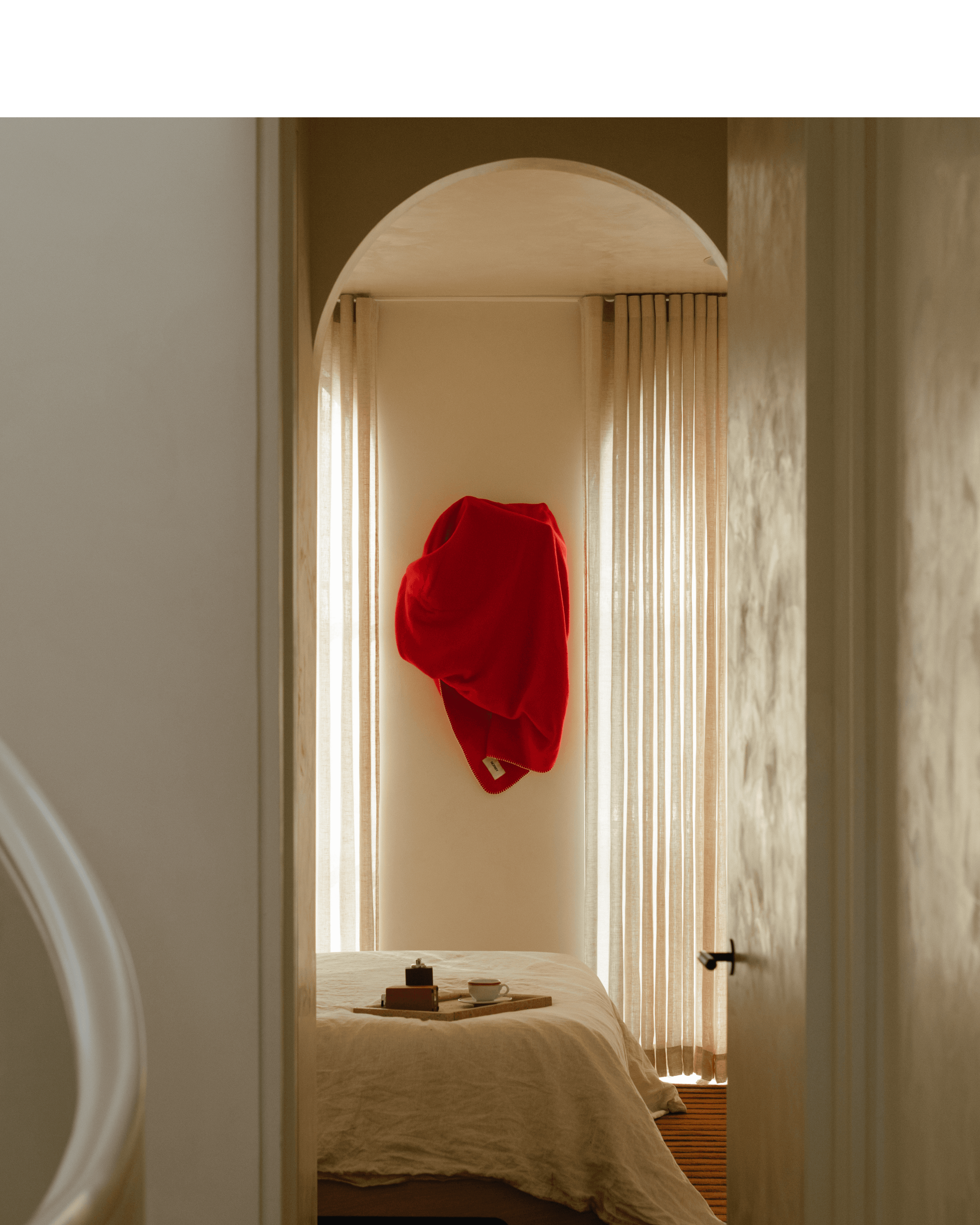 A cozy scene showing a person dressed in white lounging on a sofa, surrounded by plush blankets in cream and deep teal. Both blankets feature the "NORMY" label, highlighting the brand, and add a touch of comfort and style to the setting, which also features colorful tile flooring.
