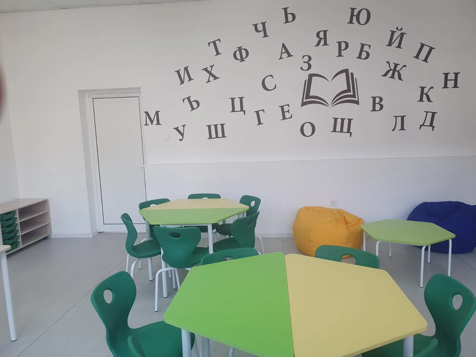 Modern learning room with green school chairs, classroom tables, and reading wall graphics