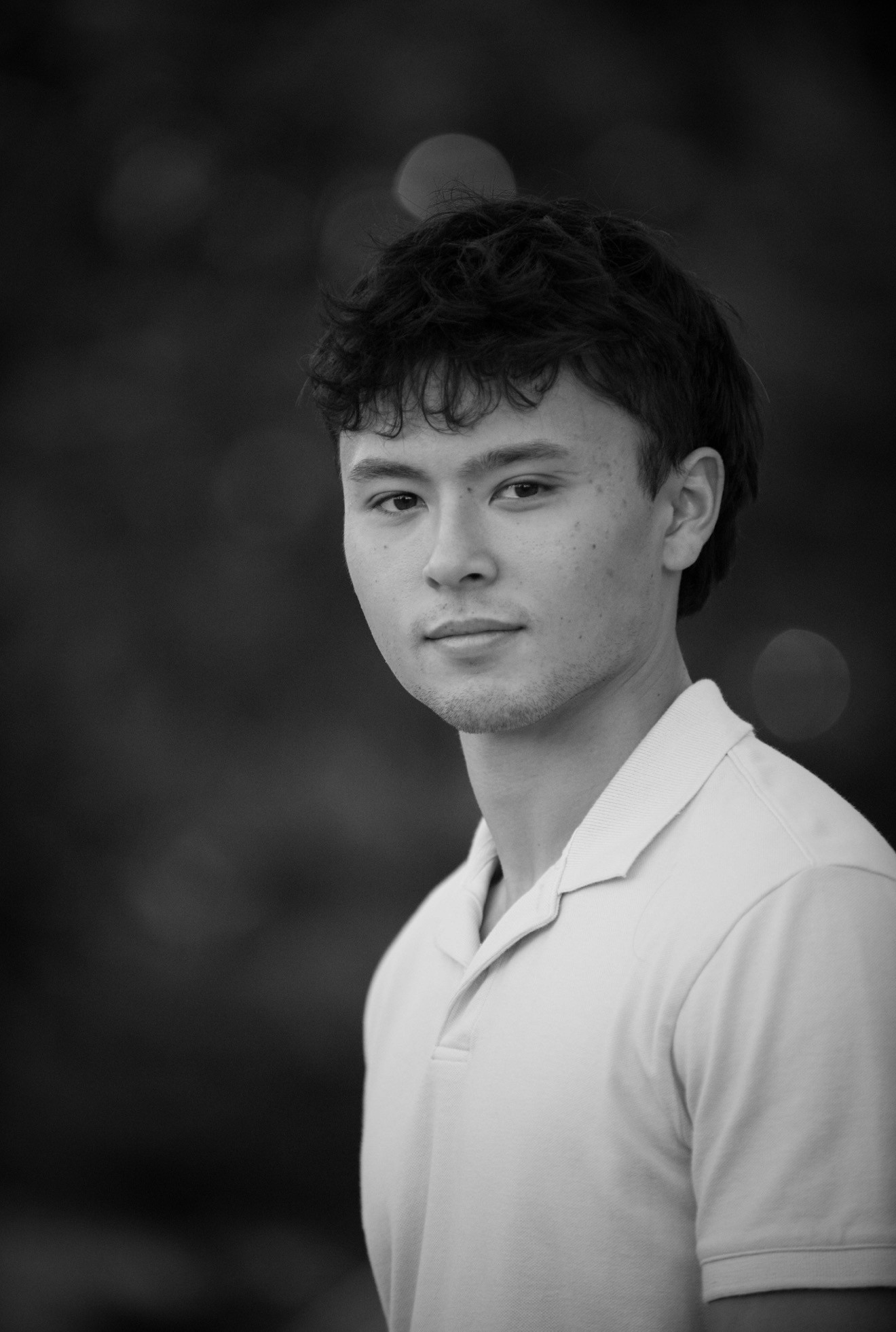 Young woman in a white shirt with a colorful gradient print, against a plain background.