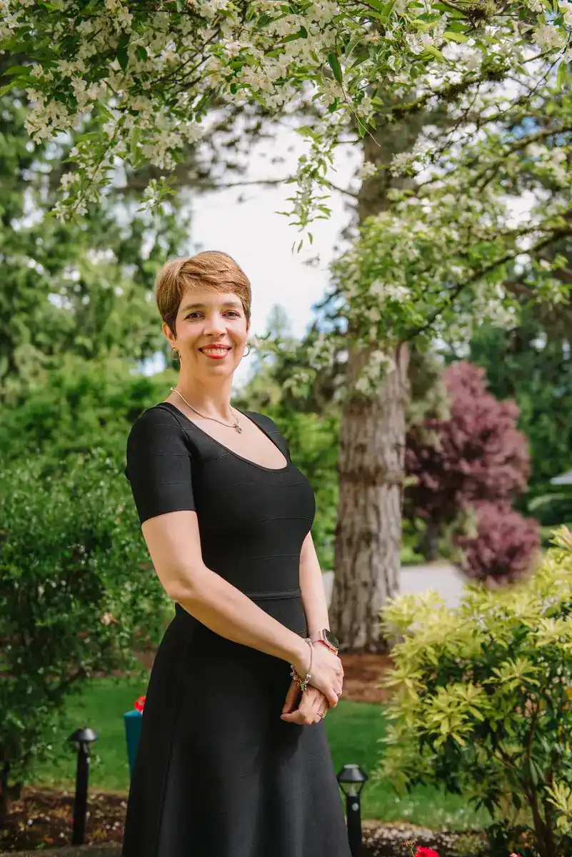 Outdoor portrait of Dr. Raluca Marinescu standing beneath flowering trees.
