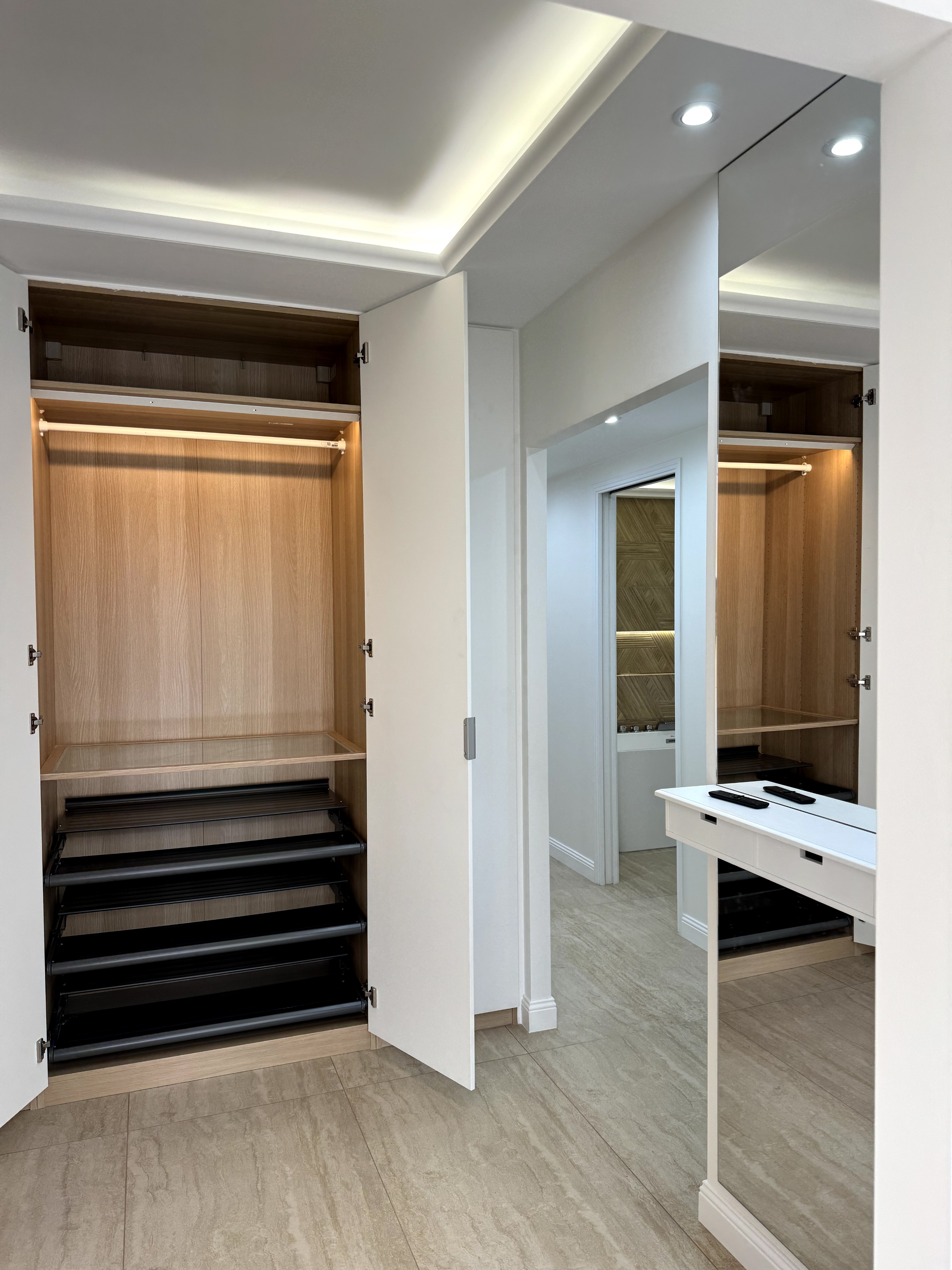 Dressing sur-mesure ouvert en bois clair avec éclairage LED automatique intégré aux étagères.