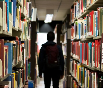 aluno buscando livro ideal em biblioteca