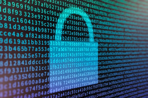 A person walks in front of large stone arches with dark doors, flanked by tall columns, in a historic building.