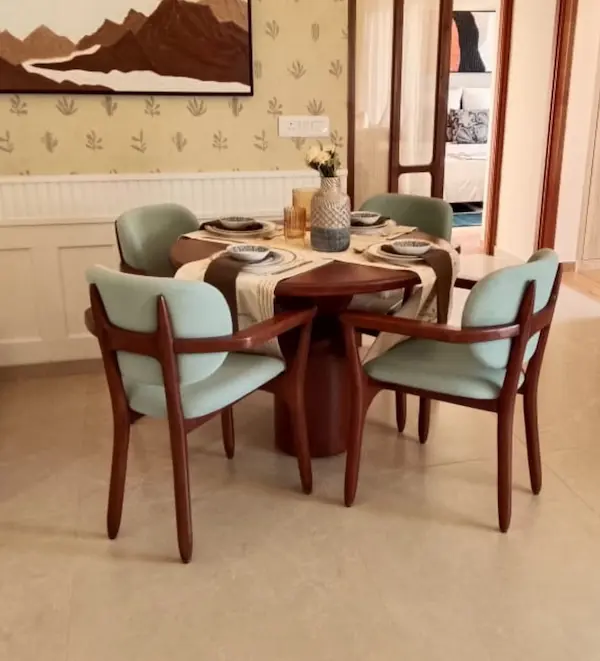 Contemporary round wooden dining table with upholstered armchairs in a refined interior