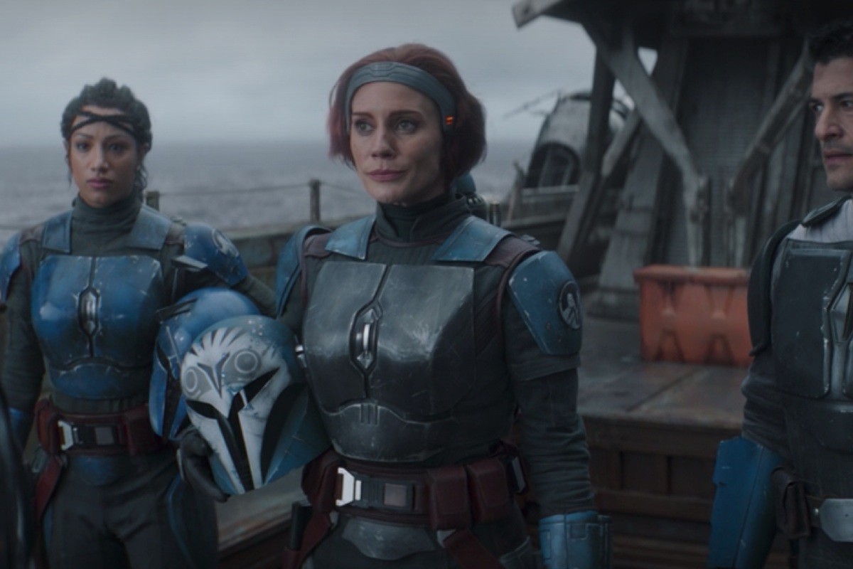 Three characters in dark armor stand on a ship deck, facing the camera with a cloudy, overcast sky behind them.