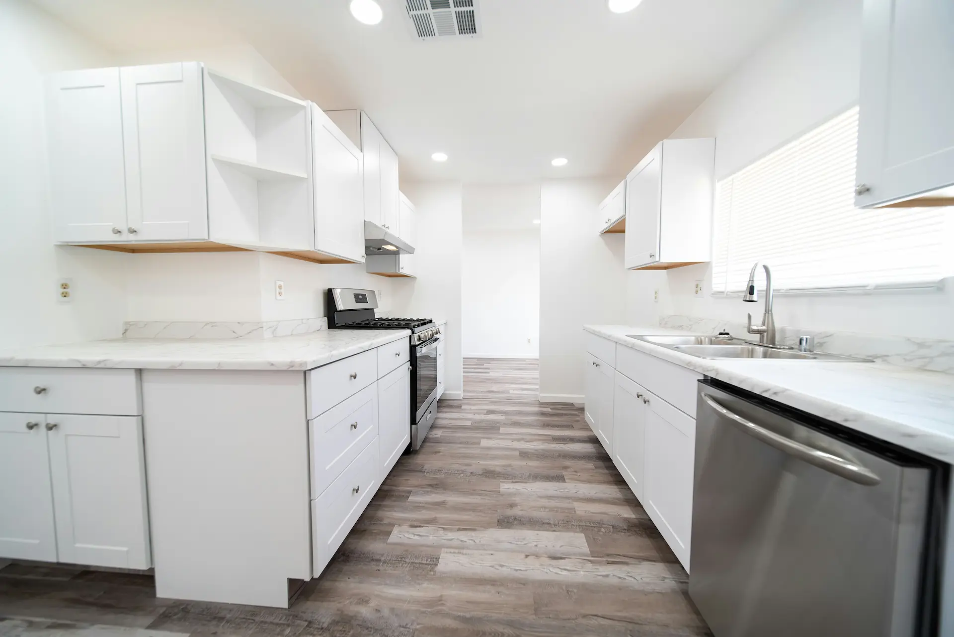 Professionally cleaned empty kitchen with white cabinets and marble countertops for a move-in move-out cleaning service.