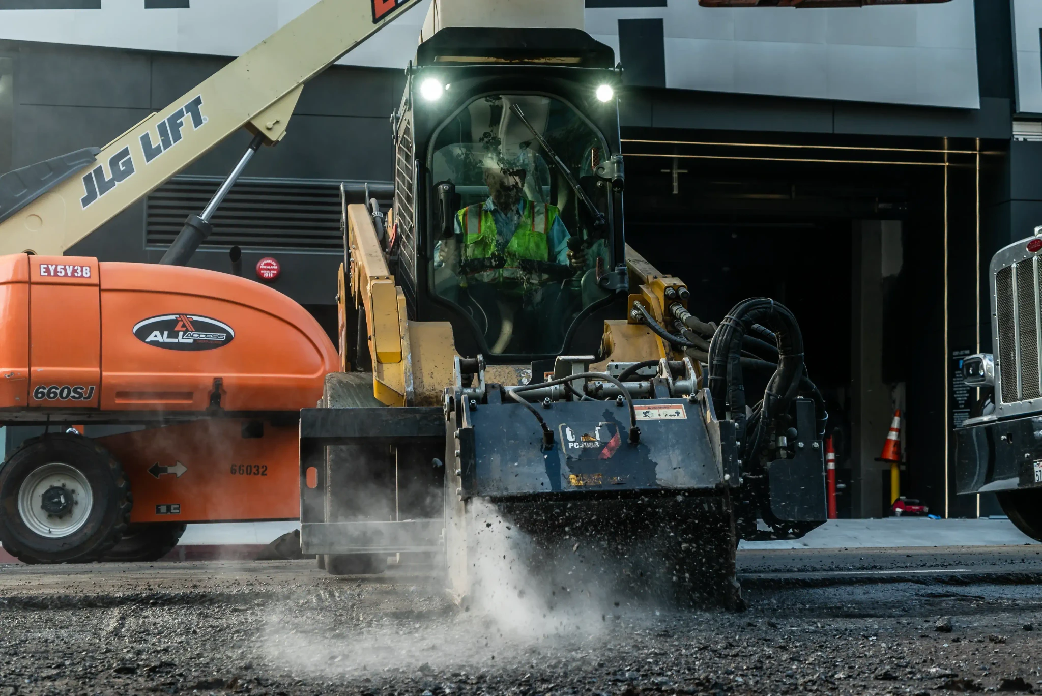 Skid steer with grinder attachment on asphalt project