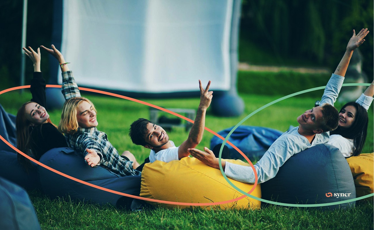 A group of young adults laughing and lounging on beanbag chairs in an outdoor setting.