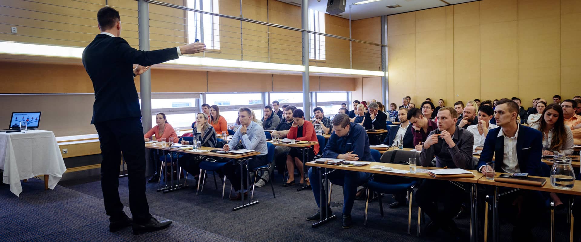 Přednášející na semináři s účastníky sedícími za stoly